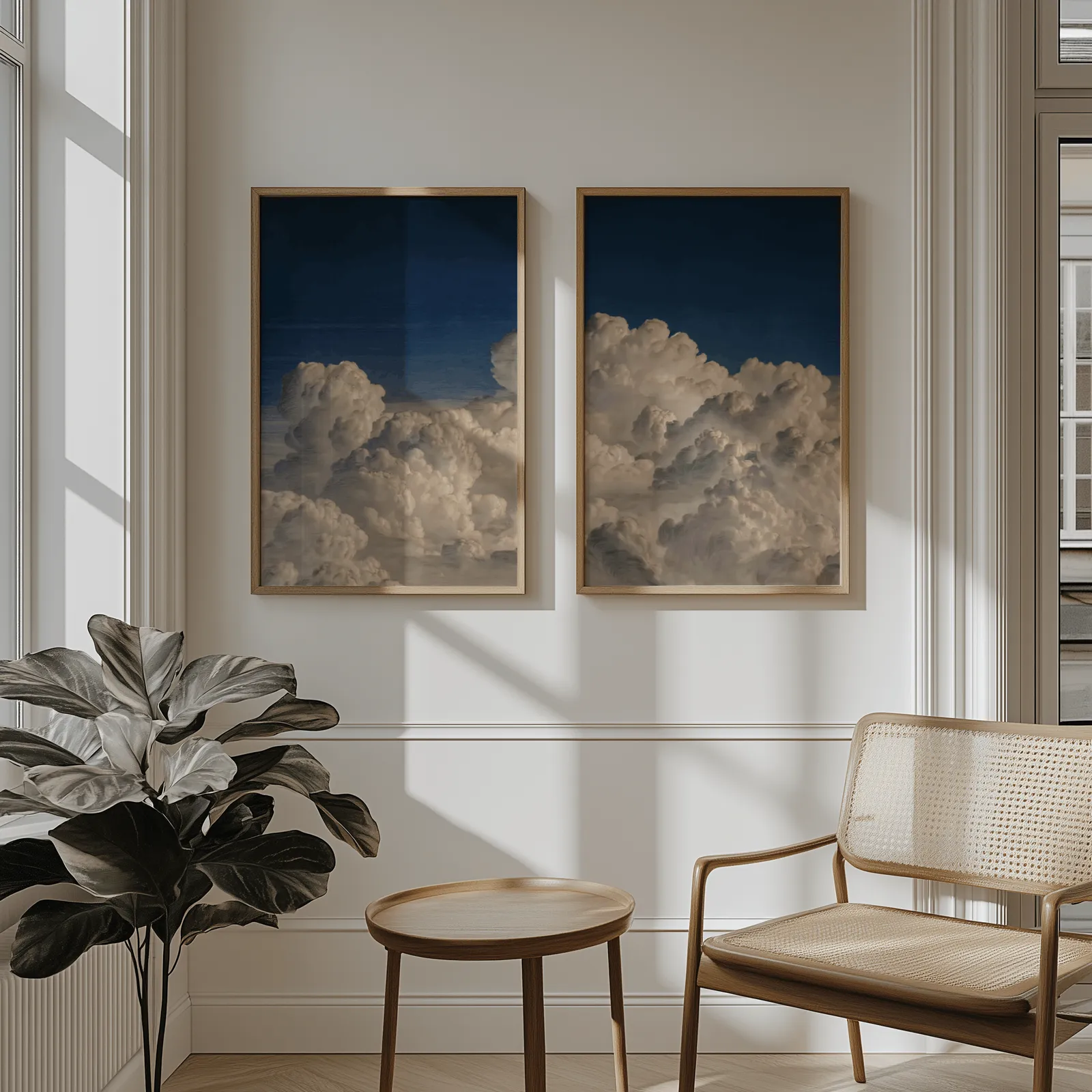 blue sky cloud landscape wall art set of two, above wainscoting beside a cane armchair and fiddle-leaf fig