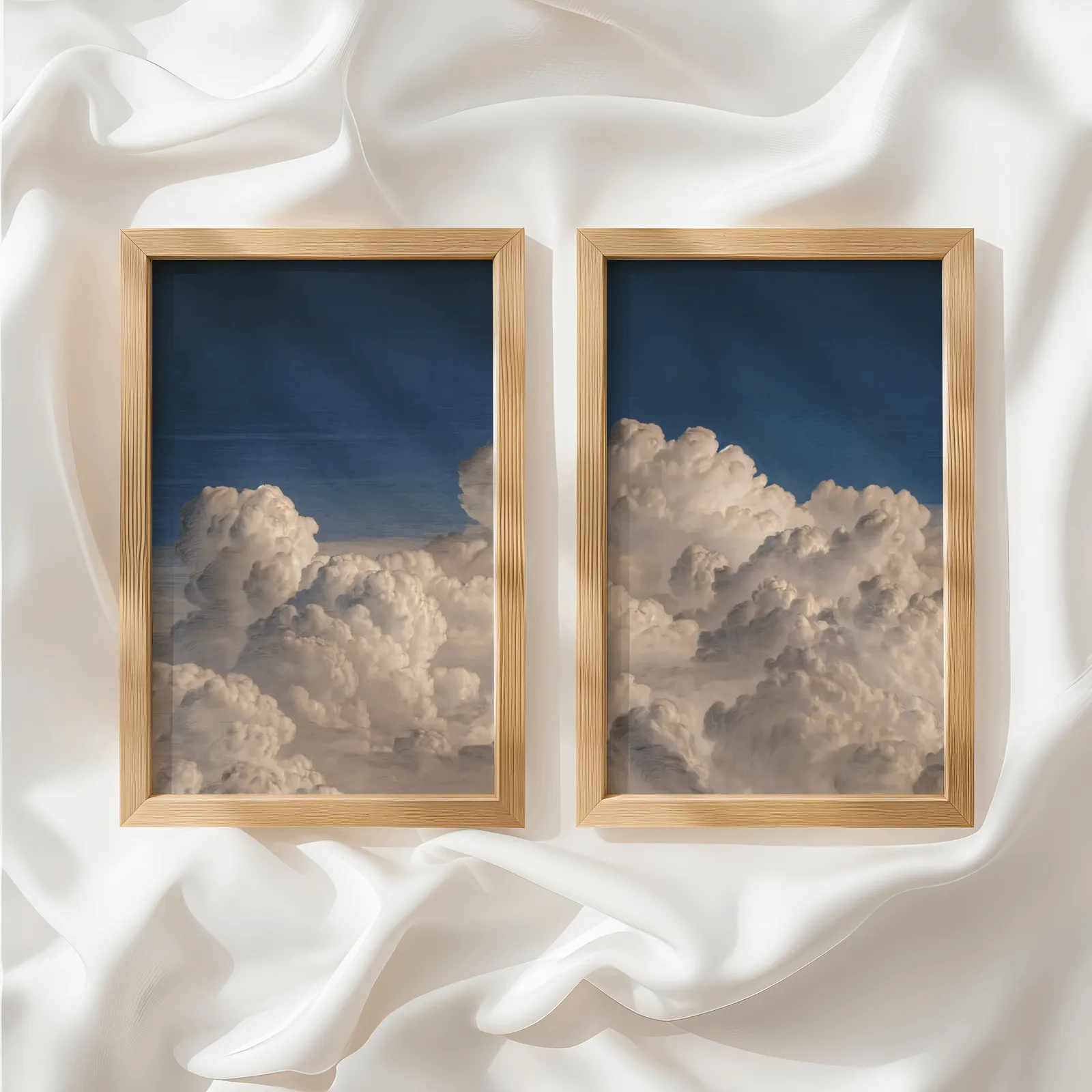 blue sky cloud landscape wall art set of two, side by side atop rumpled white silky fabric