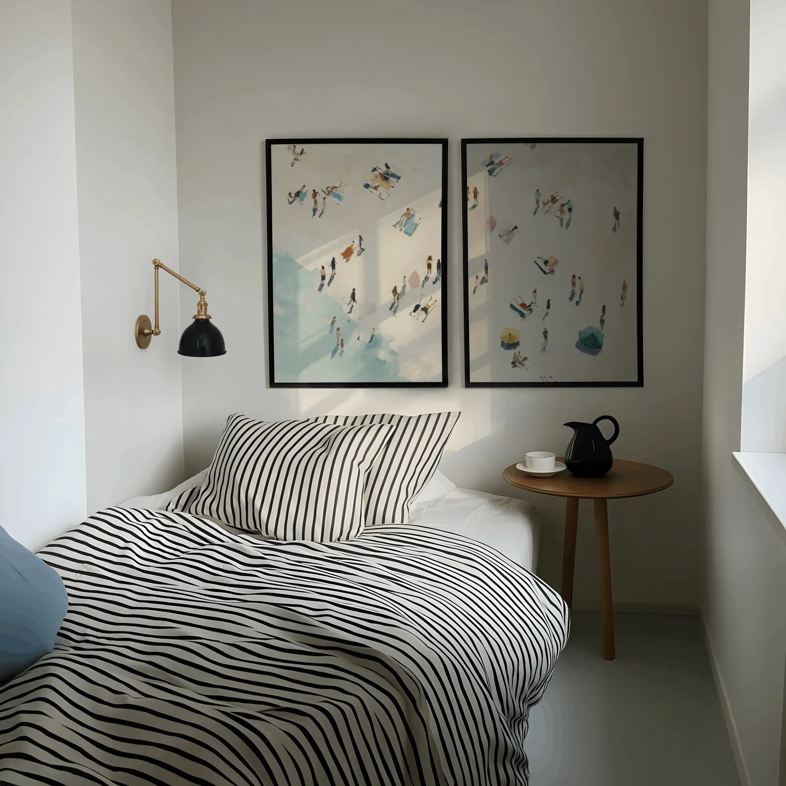 beach wall art set of 2 aerial coastal scene, above a striped bed beside a brass swing-arm lamp