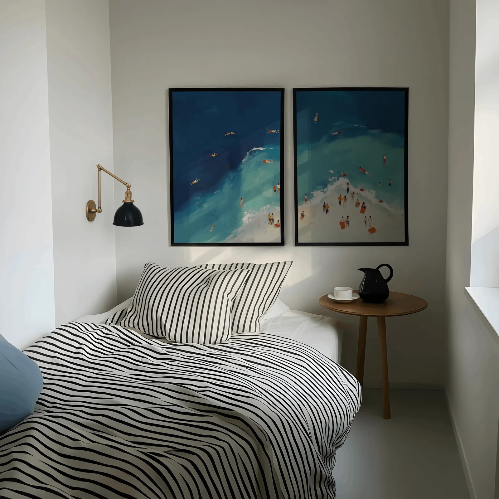 blue coastal beach wall art set of two aerial swimmers, above a striped bed beside a brass swing-arm lamp
