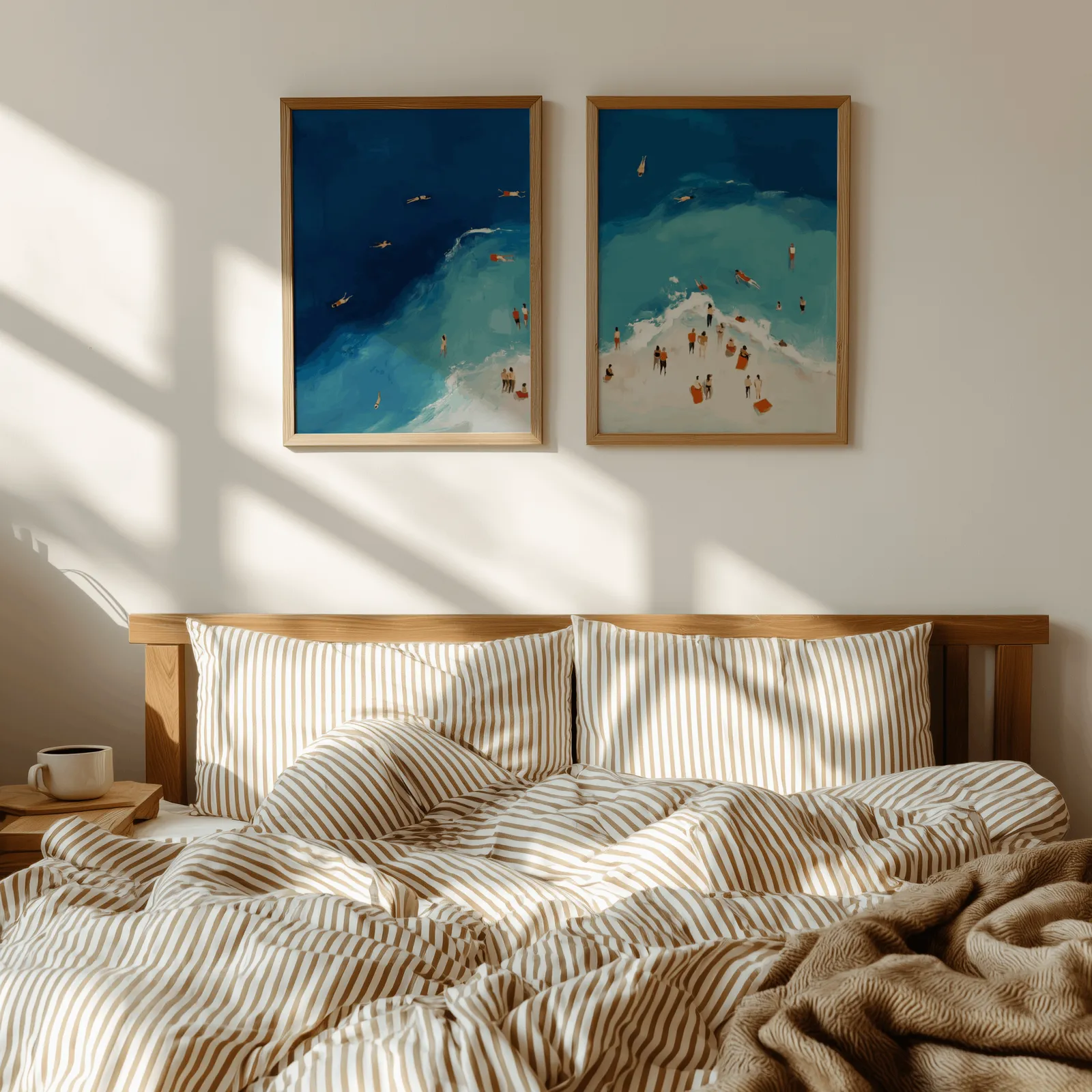 blue coastal beach wall art set of two aerial swimmers, above a wooden headboard with striped bedding and raking sunlight
