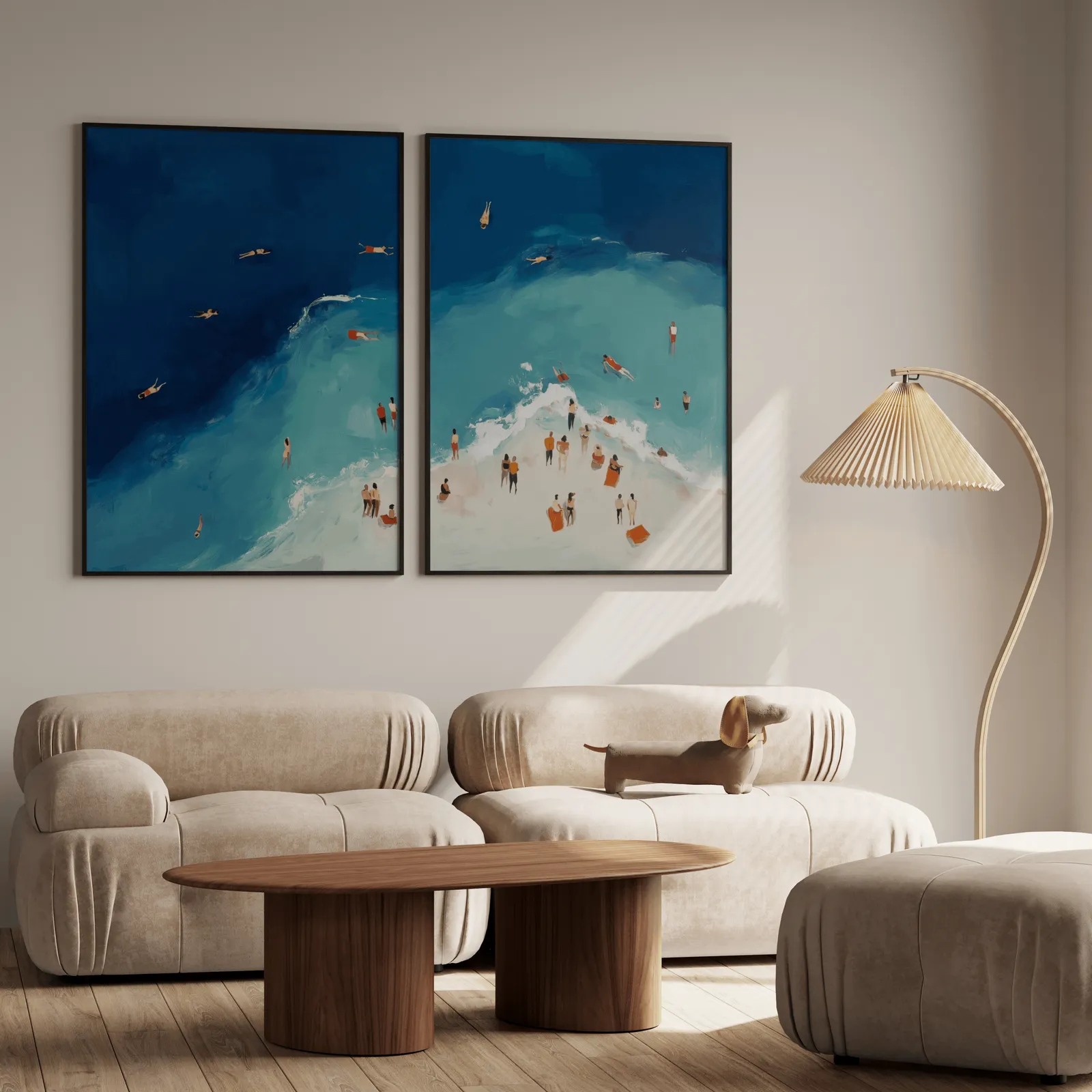 blue coastal beach wall art set of two aerial swimmers, above a plush beige sofa with a pleated lamp nearby