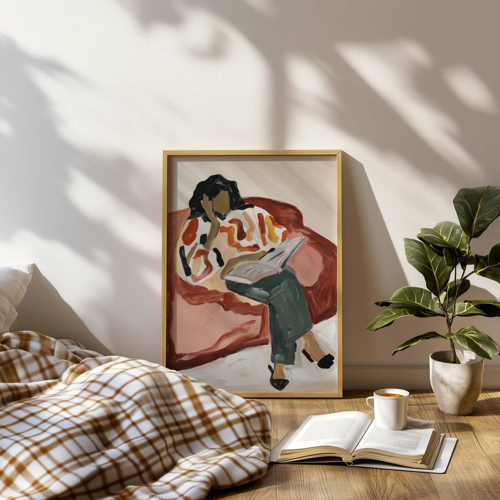 terracotta woman reading wall art, leaning on a sunlit floor beside a plaid blanket and open book