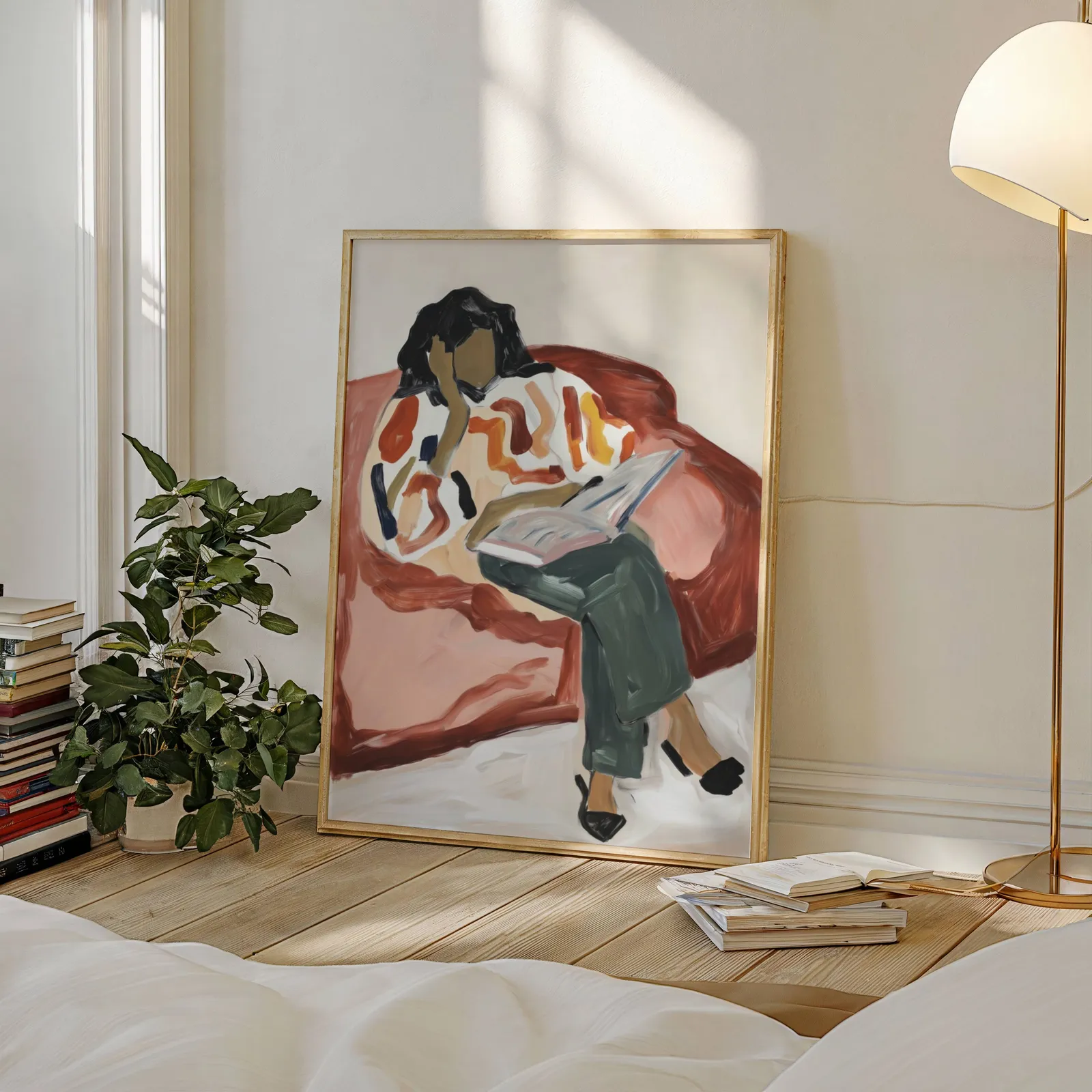 terracotta woman reading wall art, leaning against a sunlit wall beside a stacked bookshelf and fiddle-leaf plant