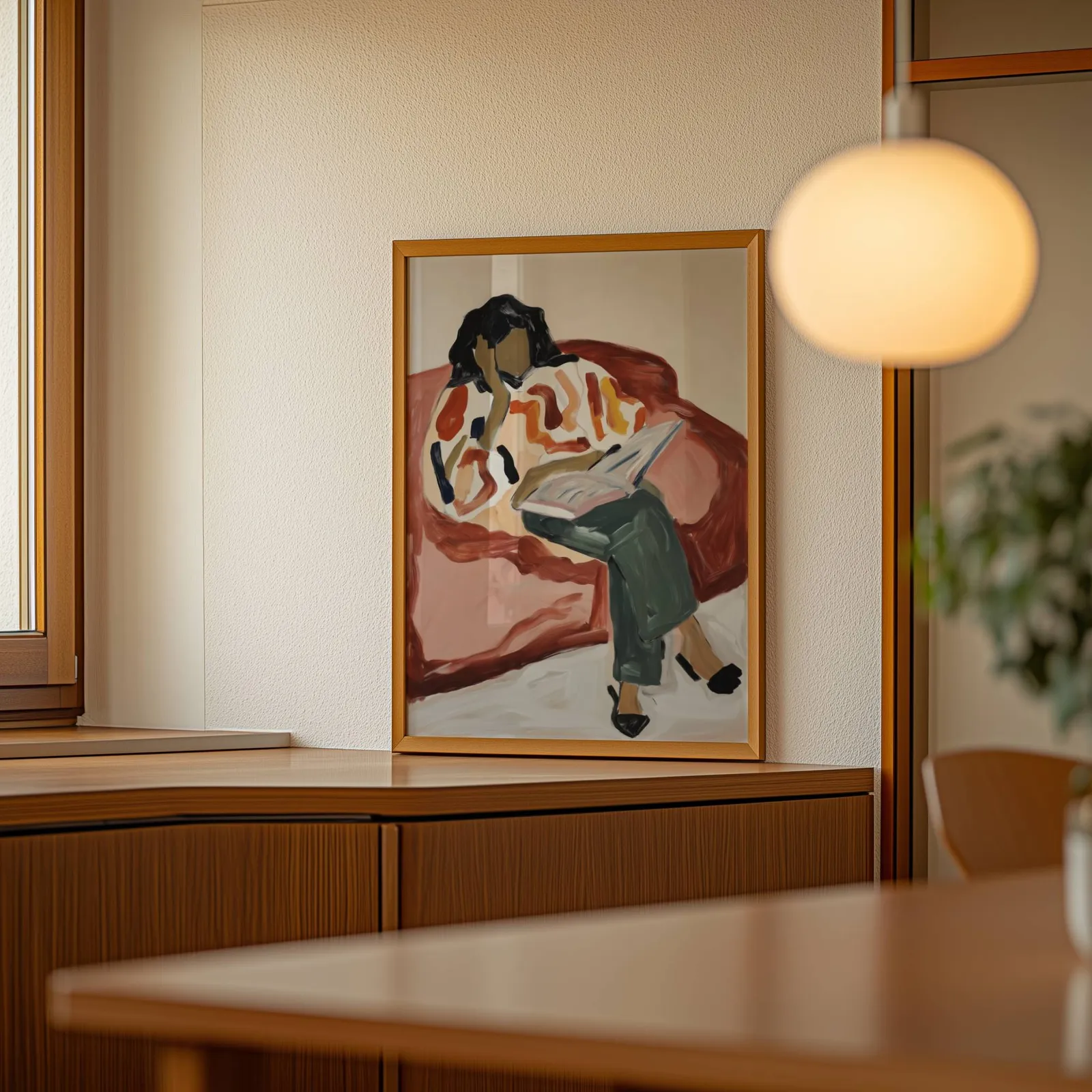 terracotta woman reading wall art, leaning on a wooden sideboard beside a glowing globe pendant