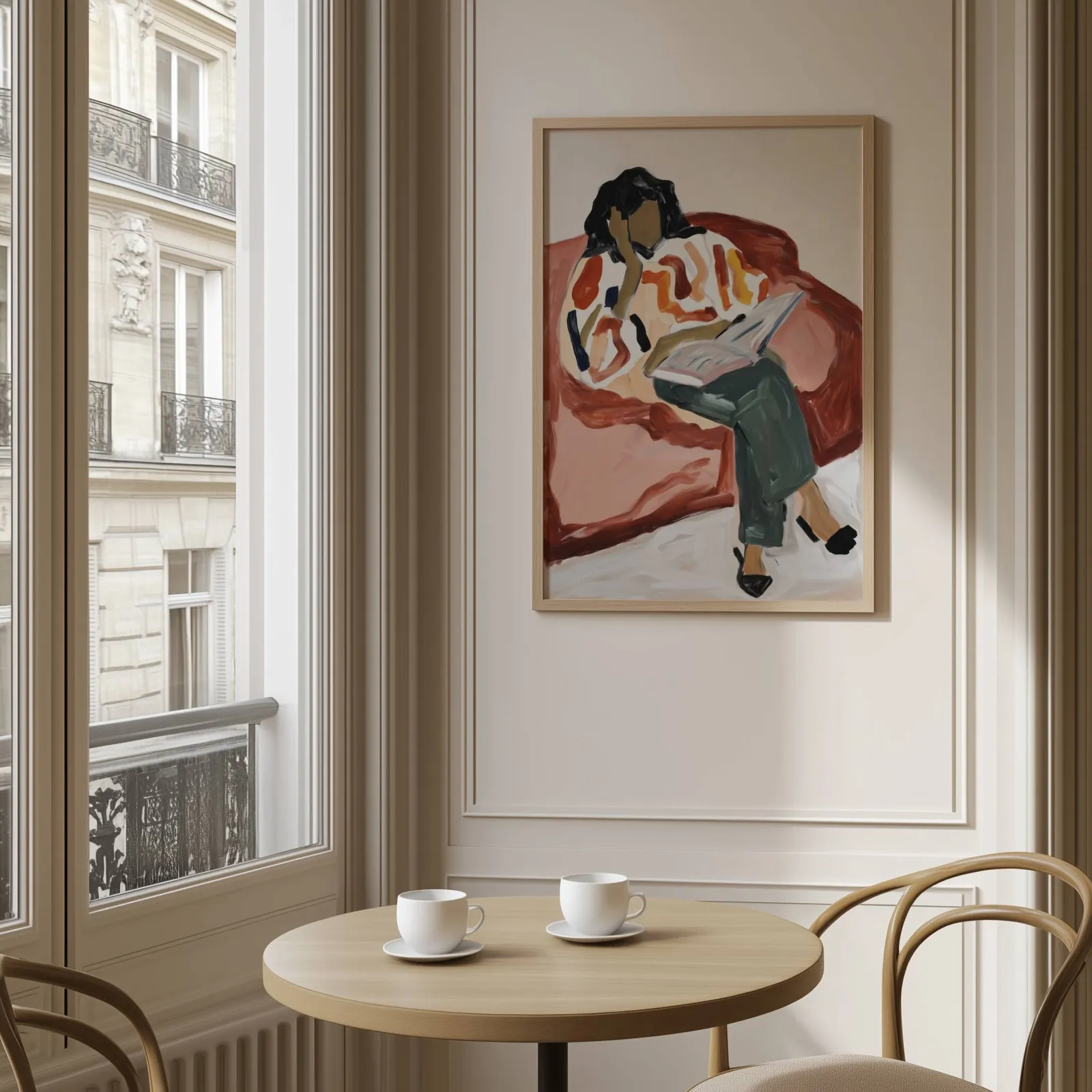 terracotta woman reading wall art, above a round café table set with two coffee cups
