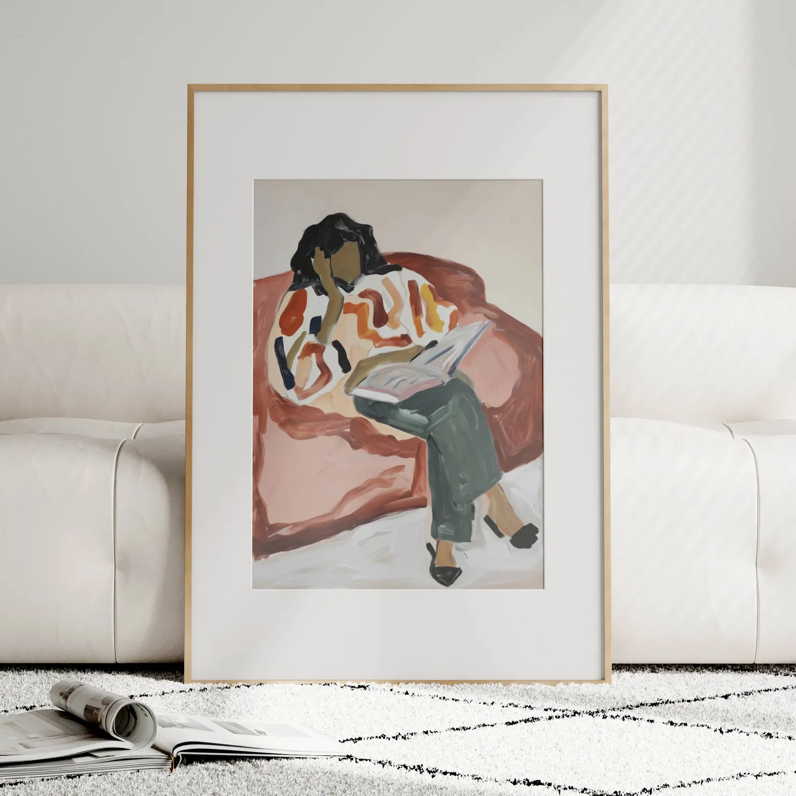 terracotta woman reading wall art, leaning against a plush cream sofa on a patterned rug