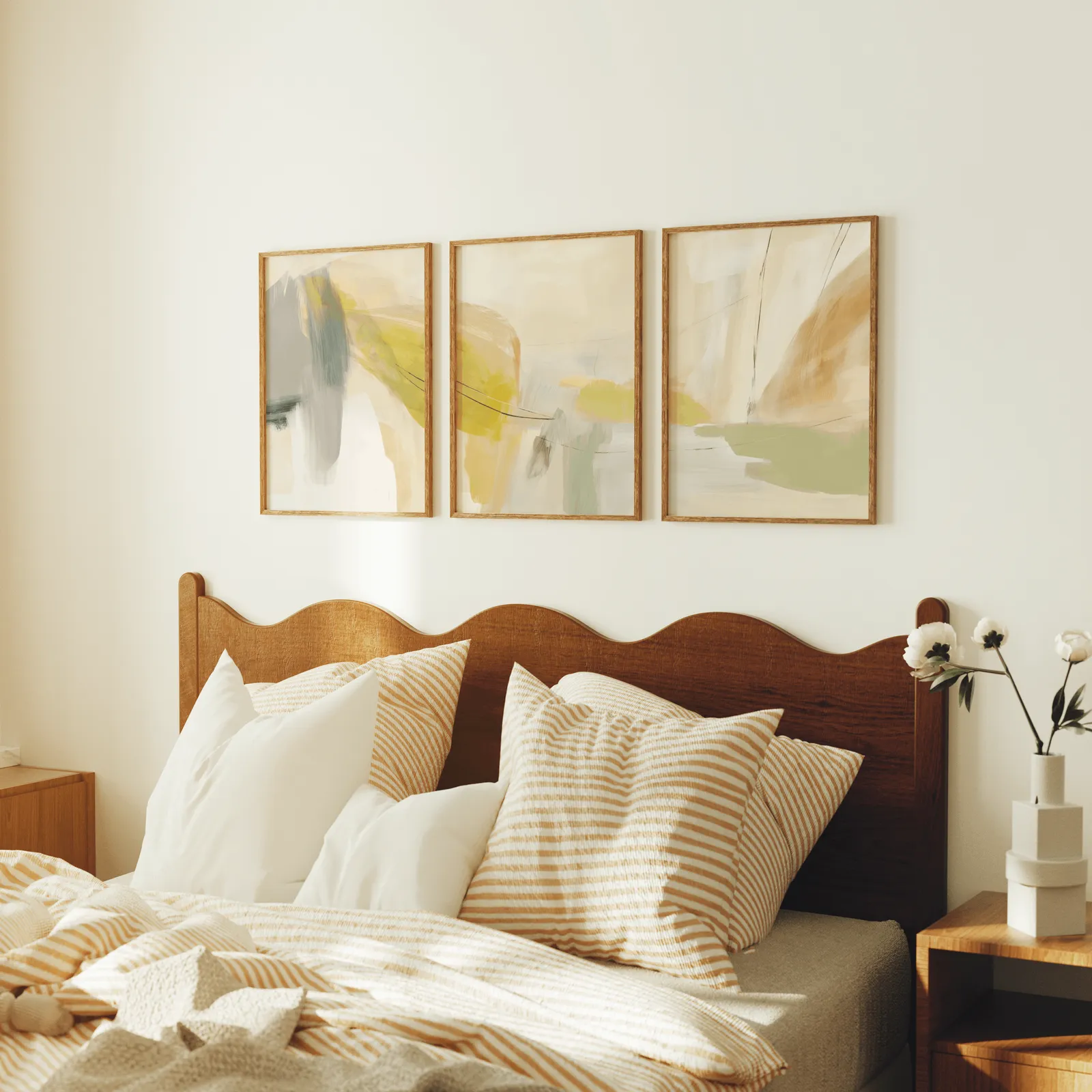 yellow and beige abstract wall art set of 3, above a scalloped wooden headboard with striped pillows