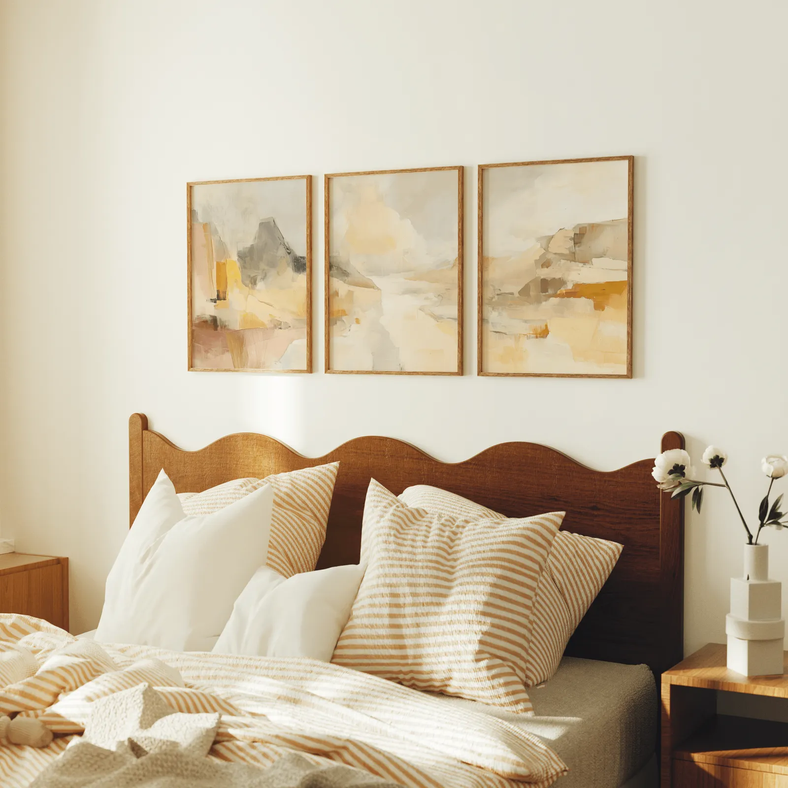 amber abstract landscape triptych wall art, above a scalloped wooden headboard with striped pillows
