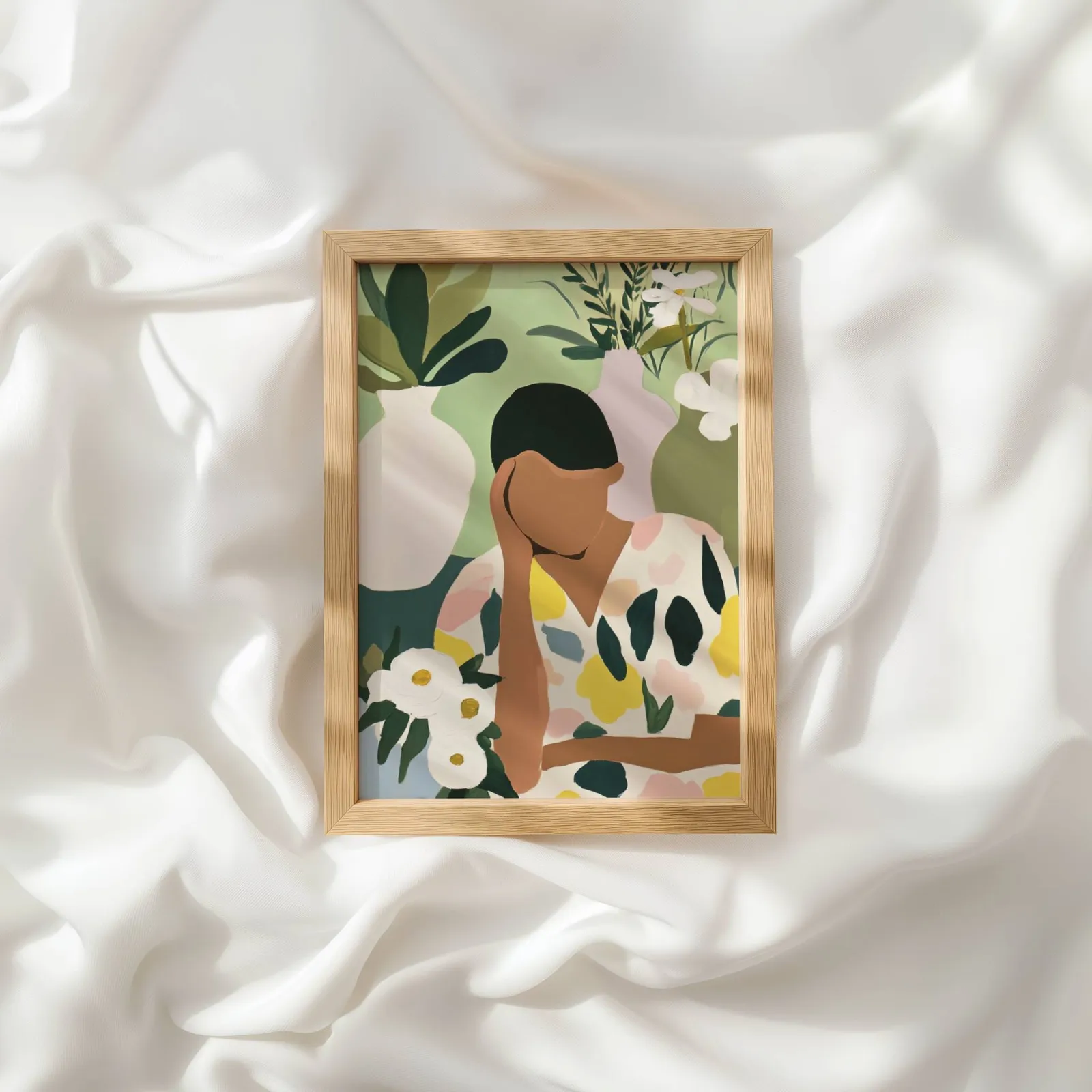 botanical woman wall art in green and cream, resting atop rumpled white silky fabric