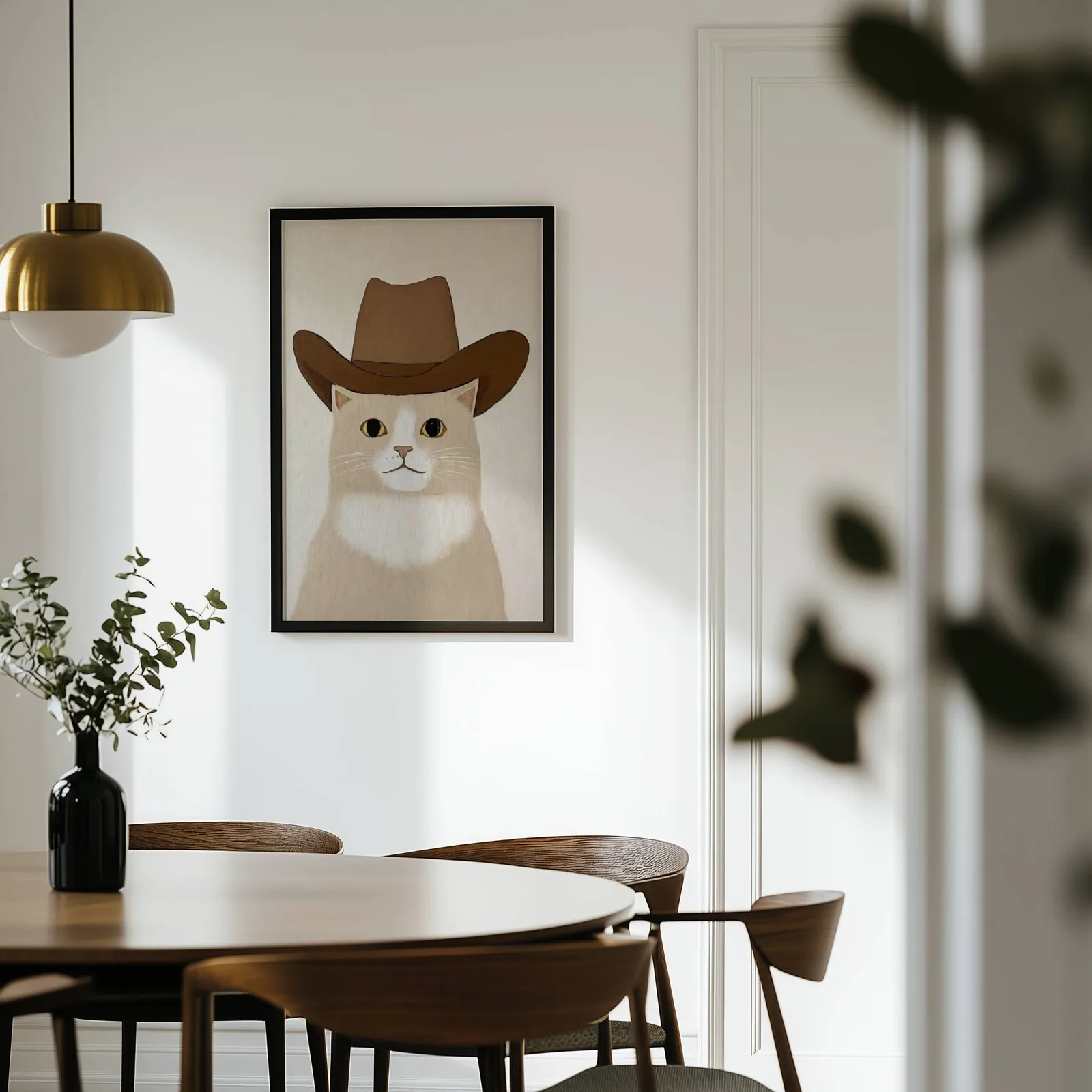 cat in cowboy hat western wall art, on a white wall above a round wooden dining table