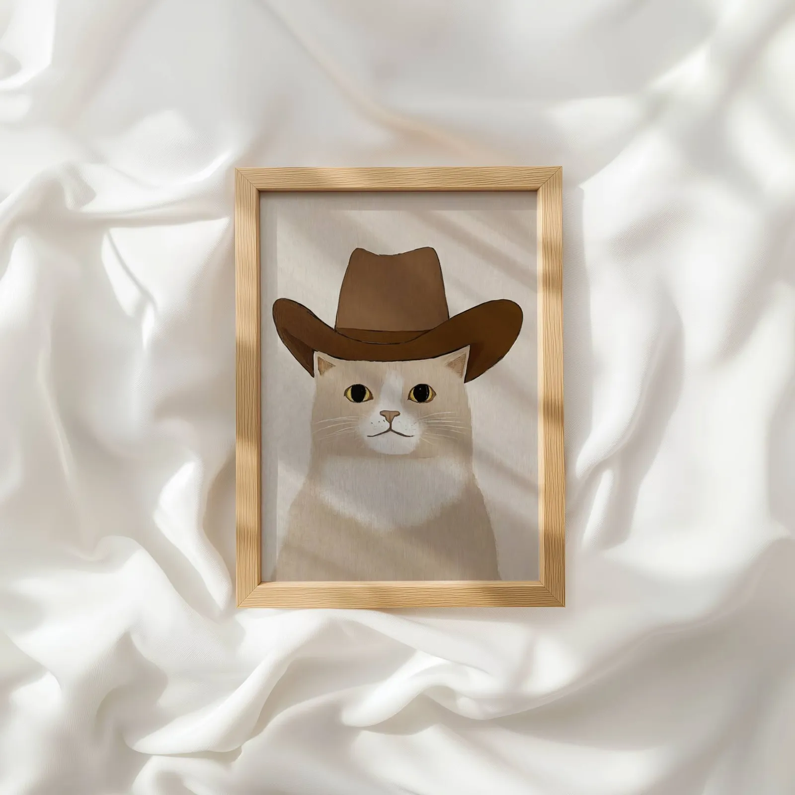 cat in cowboy hat western wall art, resting atop rumpled white silky fabric