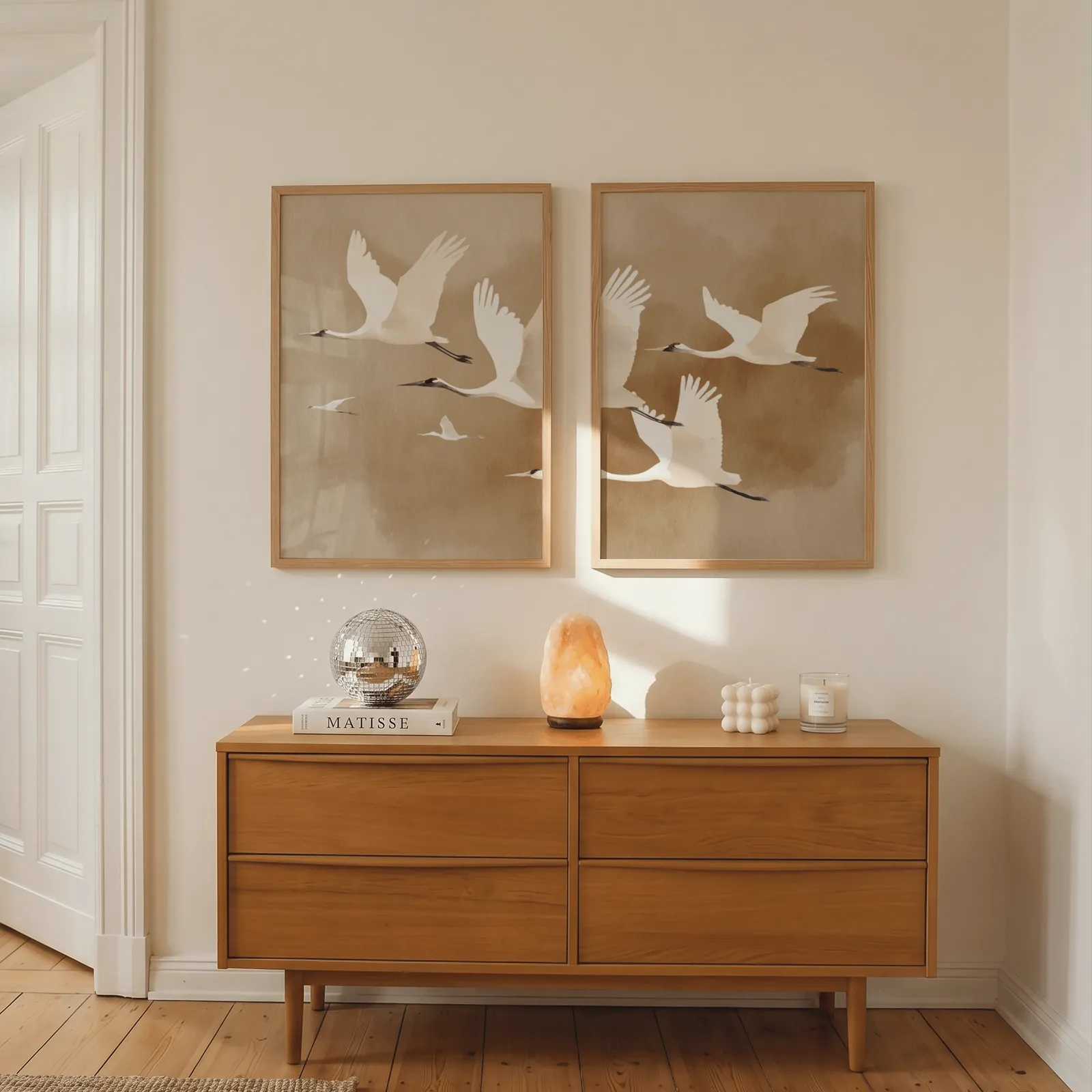 beige crane wall art set of two, above a wooden dresser with a salt lamp and disco ball