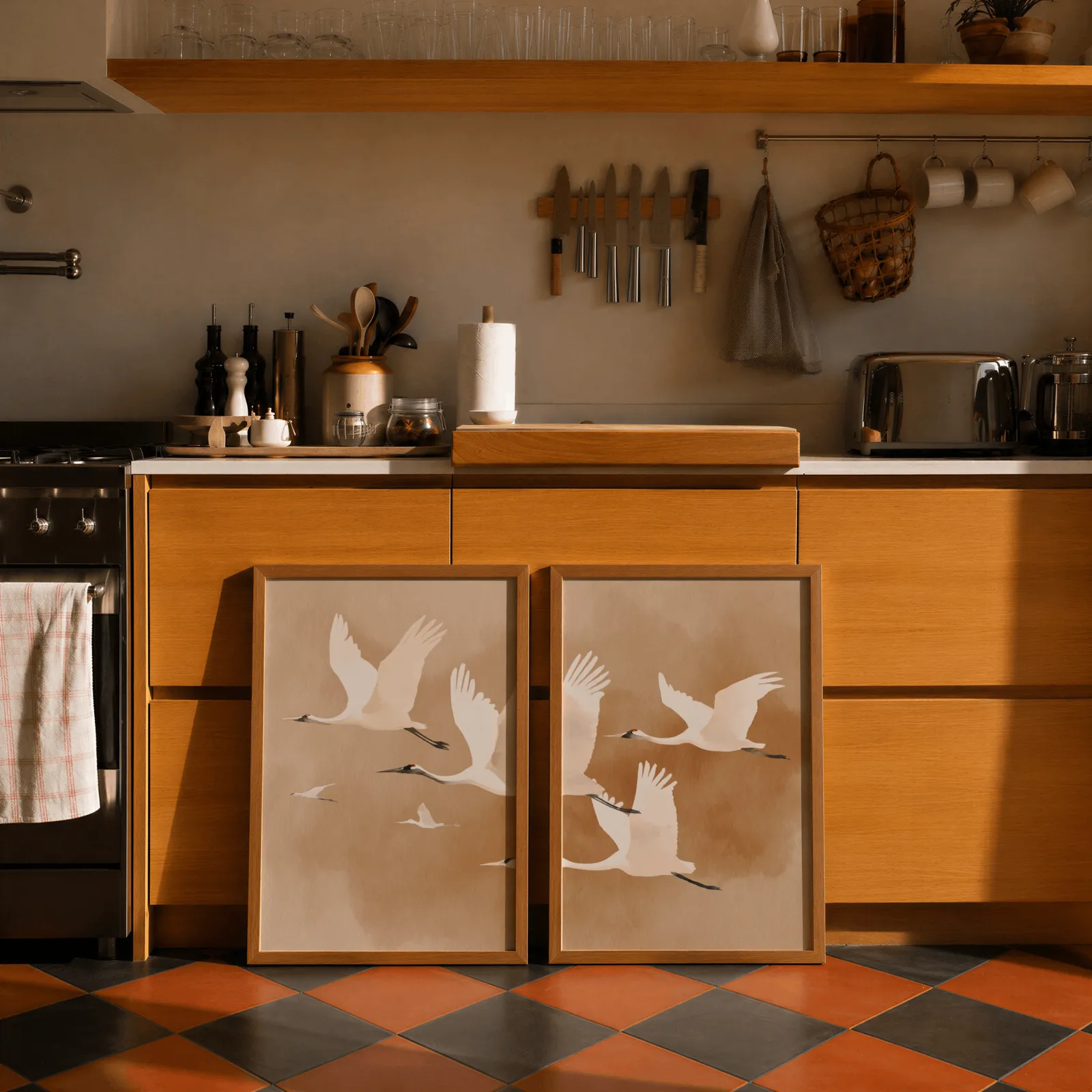 beige crane wall art set of two, leaning against wooden cabinets on terracotta tiled floor