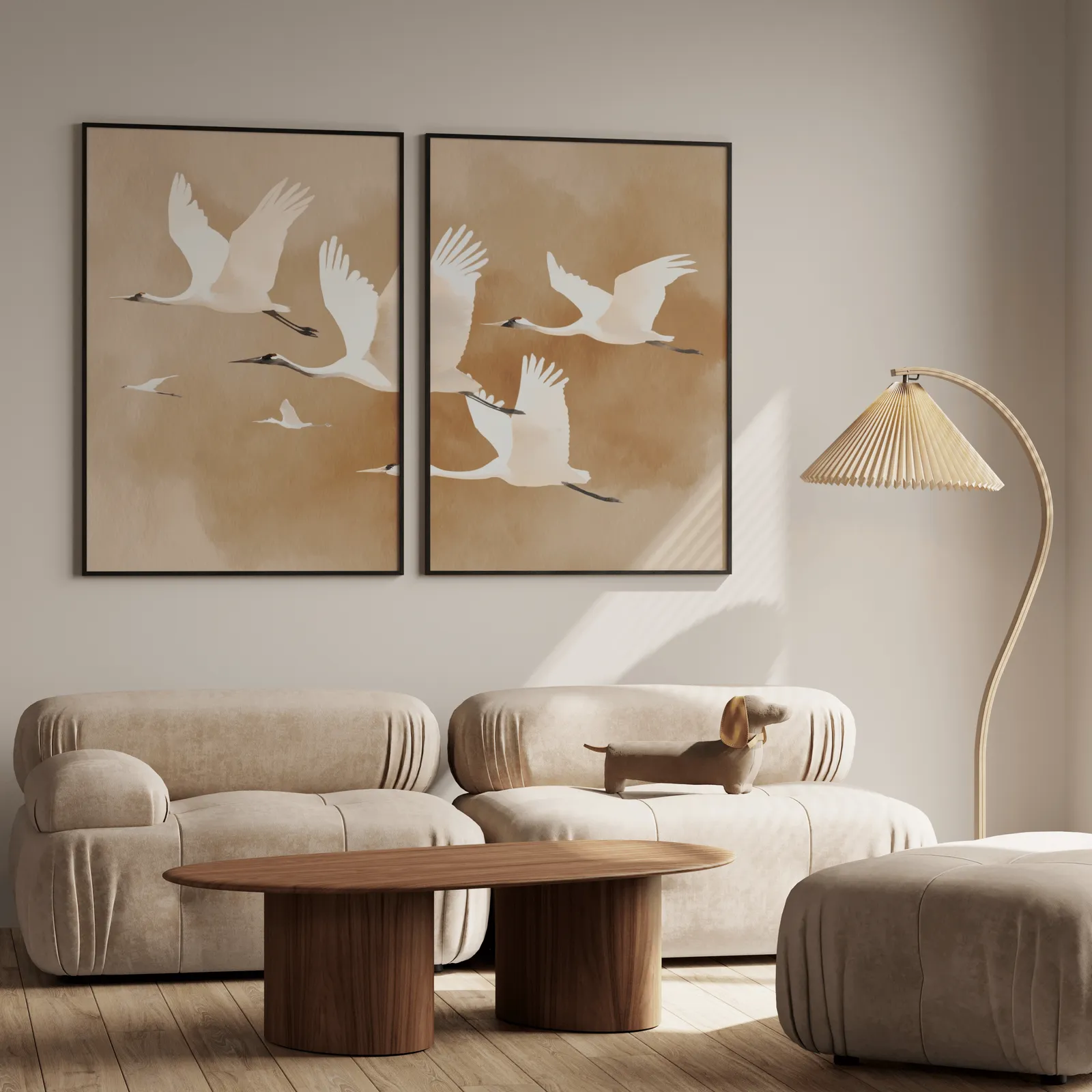 beige crane wall art set of two, above a plush beige sofa with a pleated lamp nearby