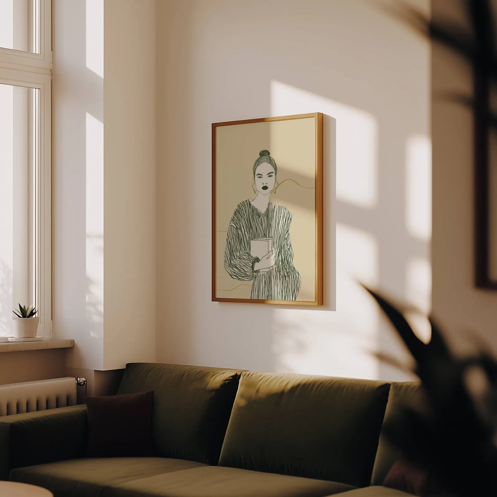 beige green modern woman reading wall art, above an olive velvet sofa in raking afternoon light