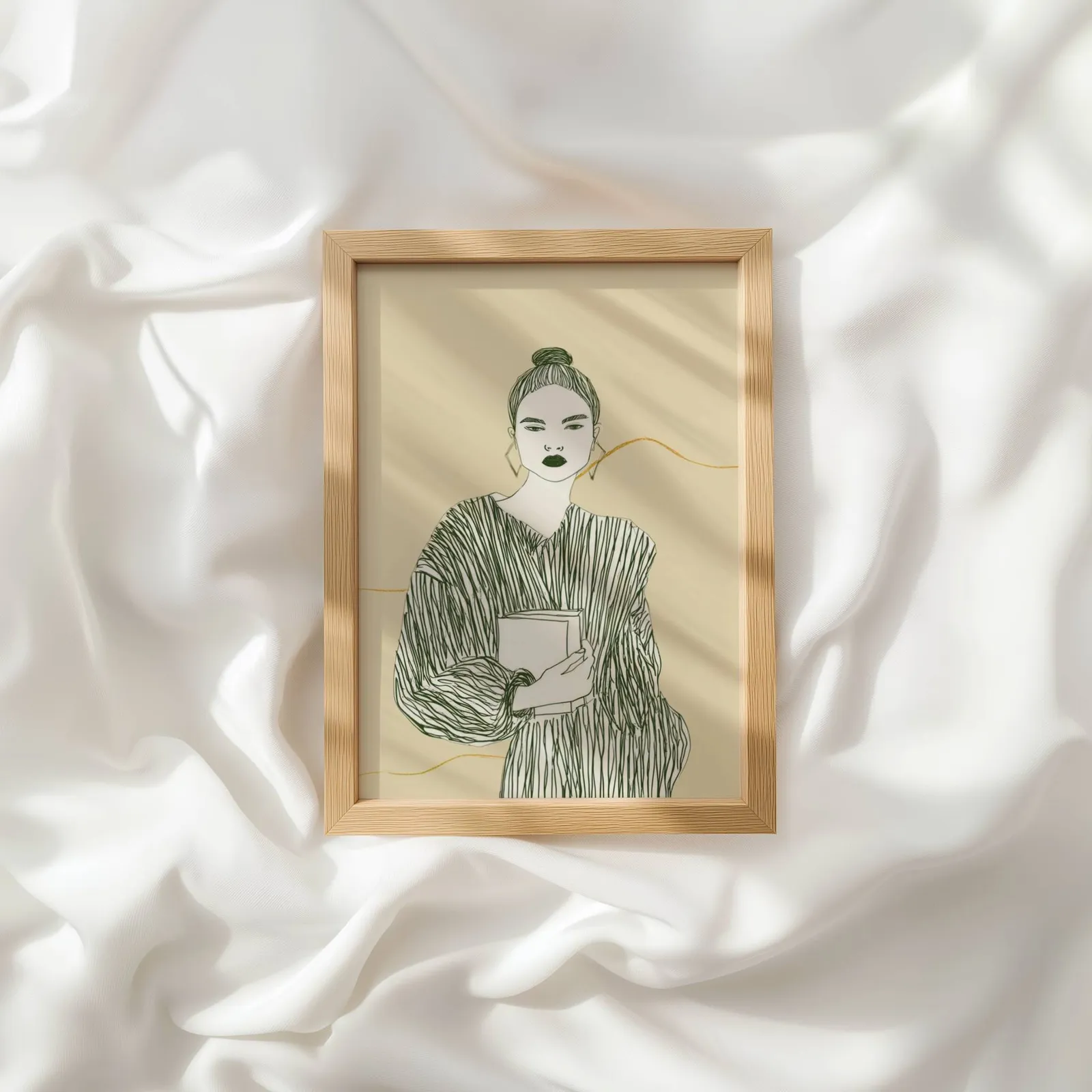beige green modern woman reading wall art, resting atop rumpled white silky fabric