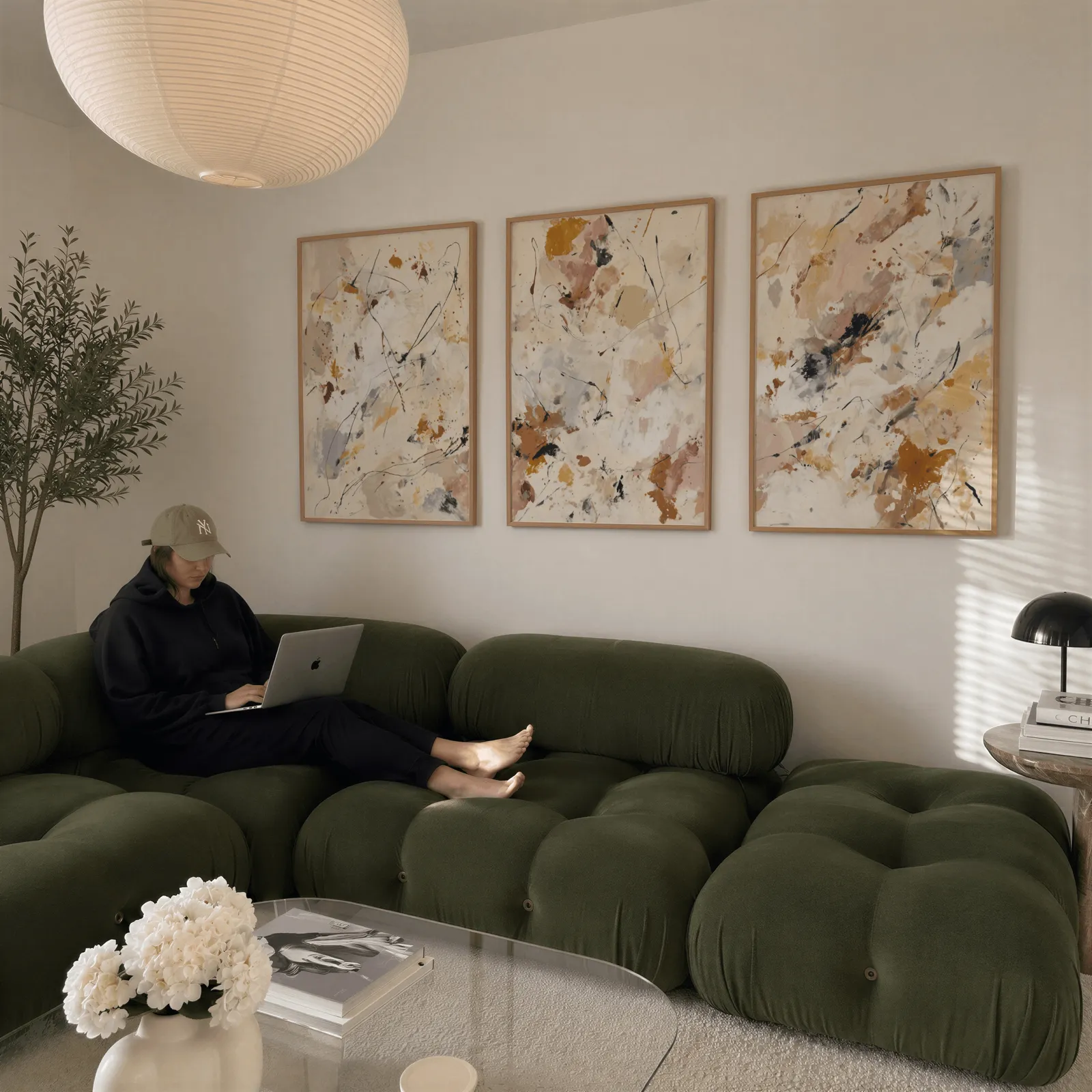 abstract neutral wall art set of 3 in terracotta and grey, above a plush olive velvet sectional beneath a paper lantern light