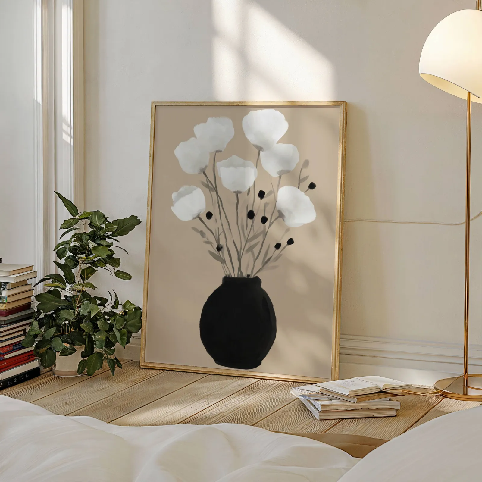 minimalist botanical wall art with black vase and white flowers, leaning against a sunlit wall beside a stacked bookshelf and fiddle-leaf plant