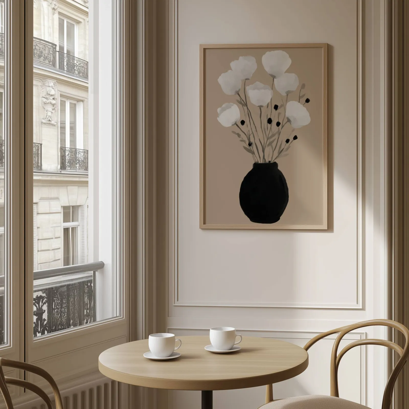 minimalist botanical wall art with black vase and white flowers, above a round café table set with two coffee cups