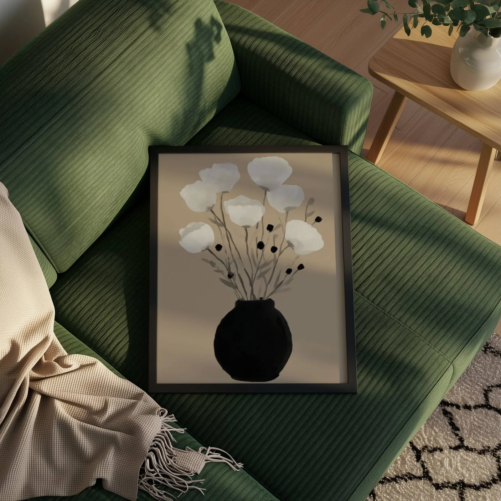 minimalist botanical wall art with black vase and white flowers, propped on a ribbed olive-green sofa beside a fringed throw