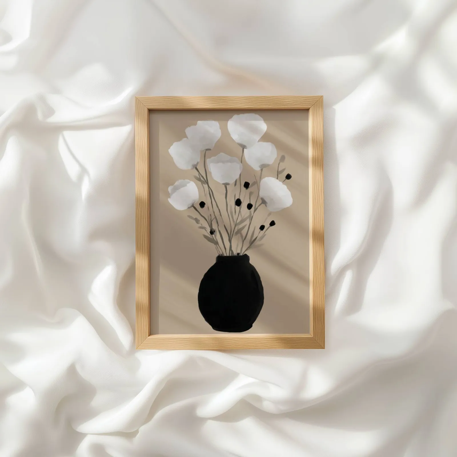 minimalist botanical wall art with black vase and white flowers, resting atop rumpled white silky fabric
