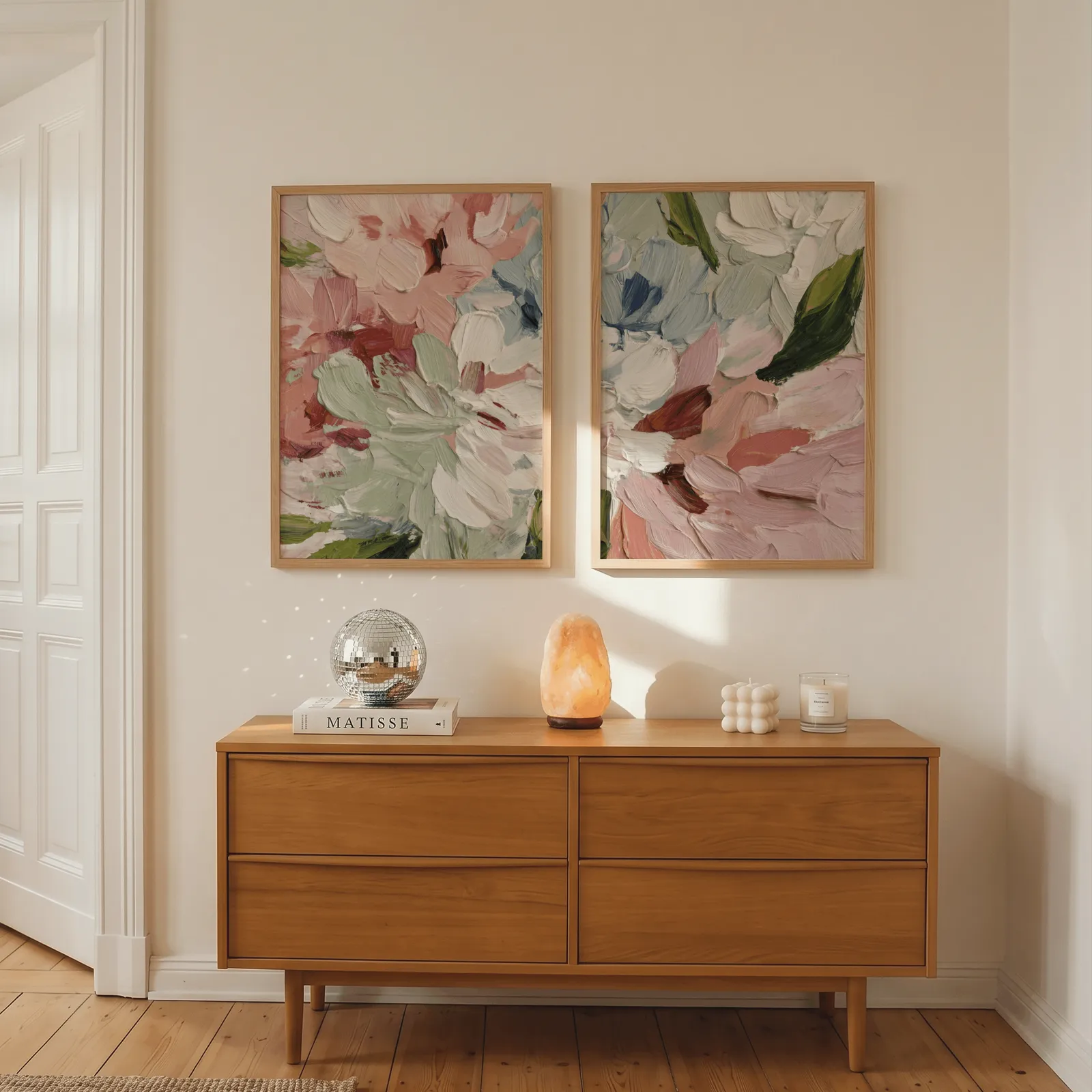 pink abstract floral wall art set of two, above a wooden dresser with a salt lamp and disco ball
