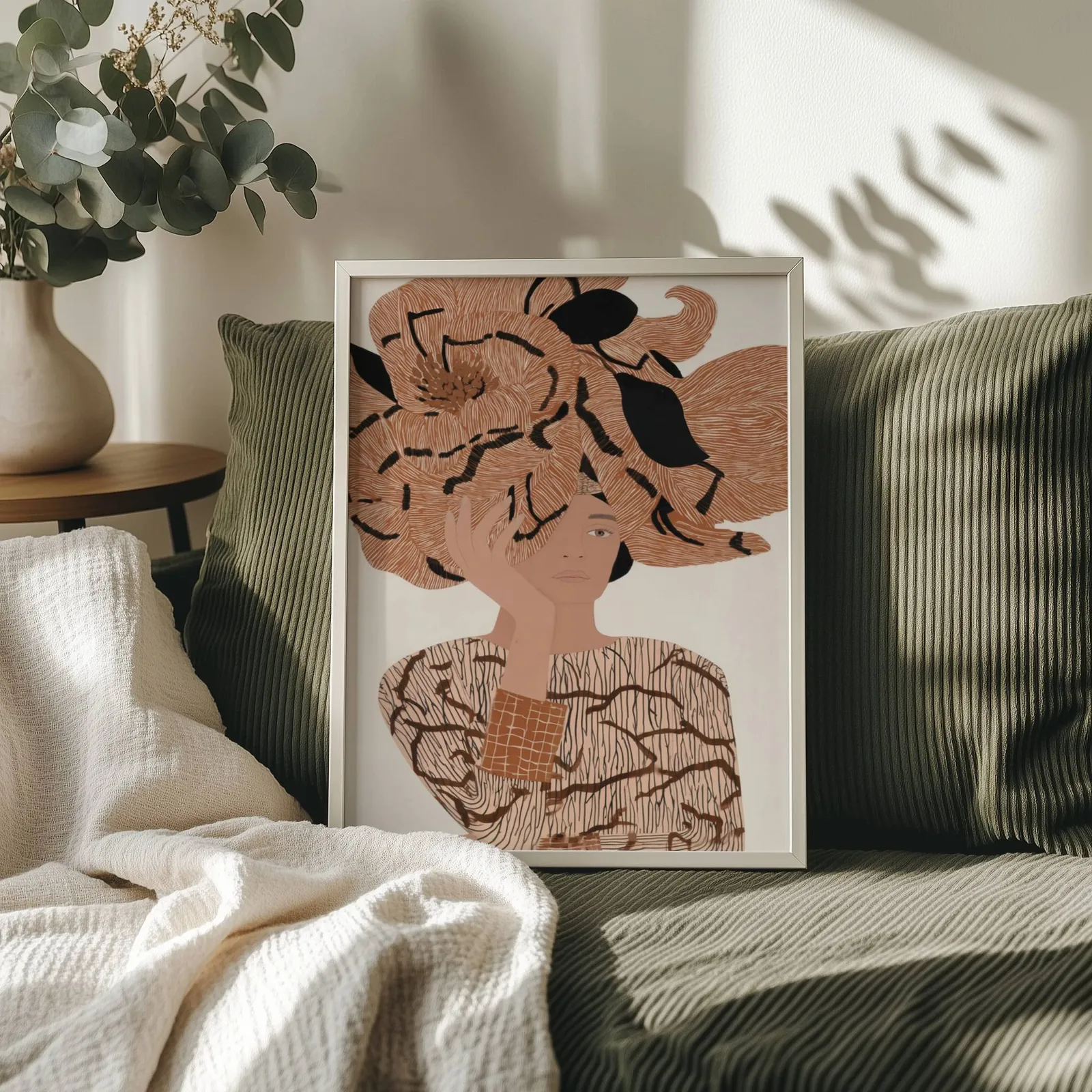 terracotta floral woman portrait abstract wall art, propped on an olive corduroy sofa beside a eucalyptus vase