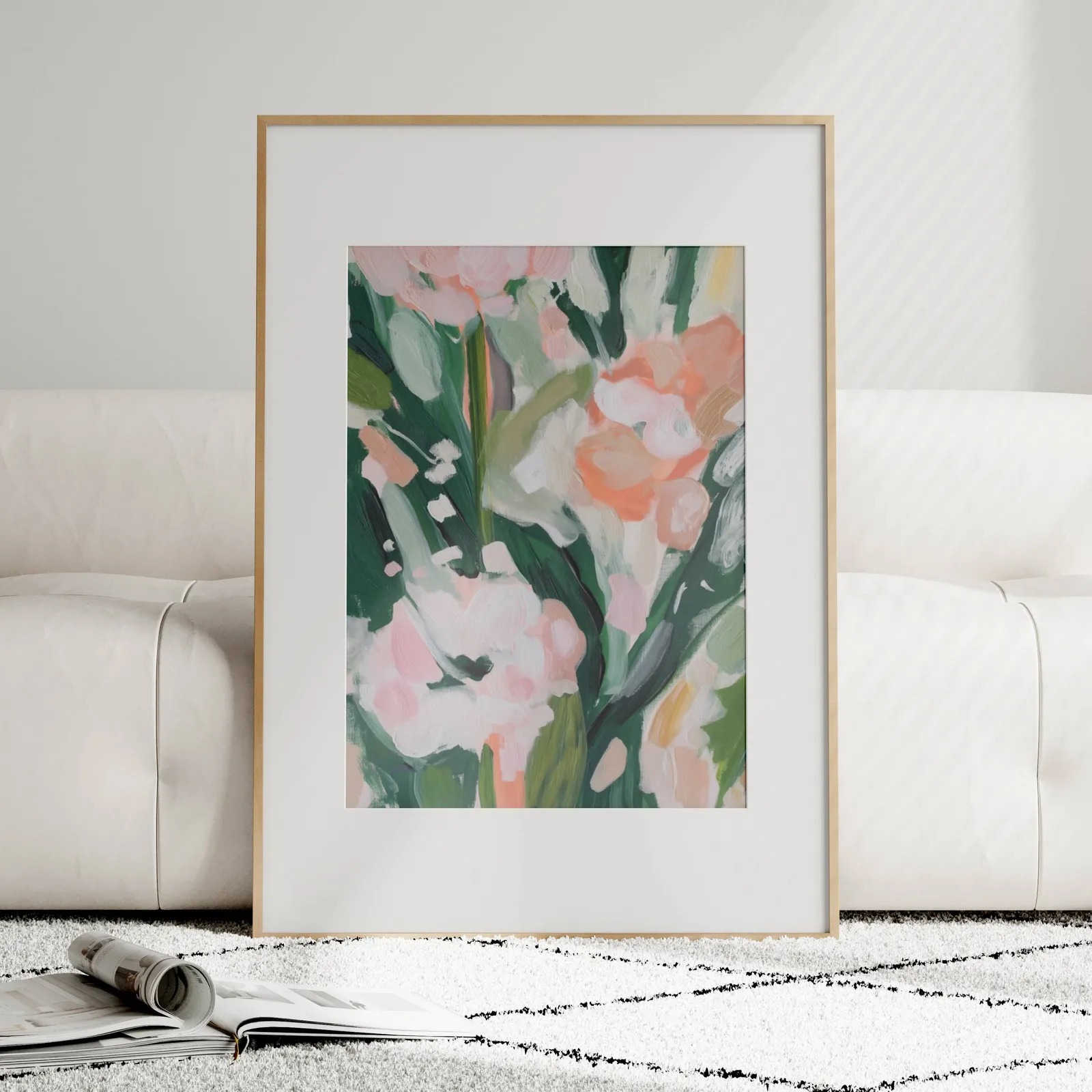 pink floral botanical wall art, leaning against a plush cream sofa on a patterned rug