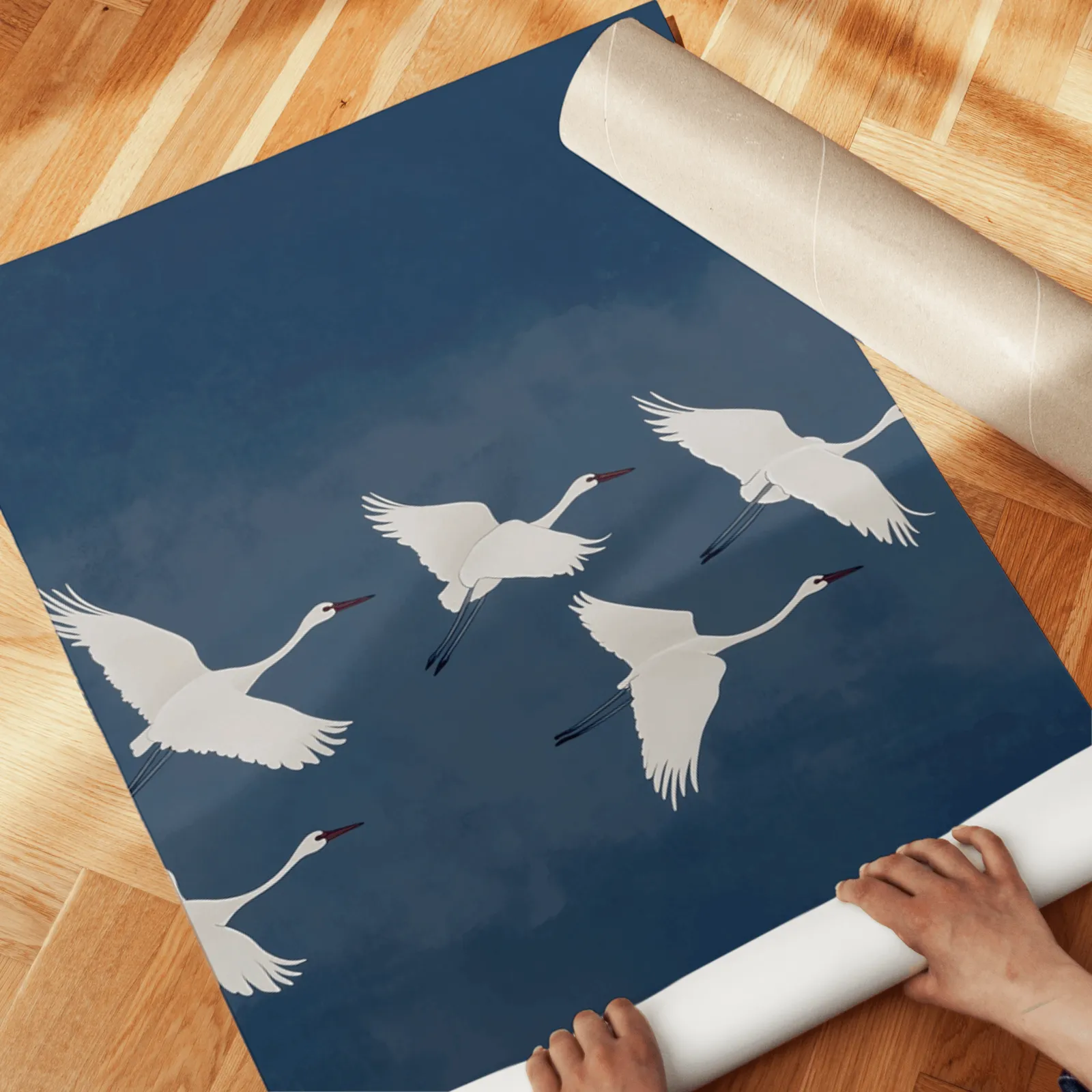 blue crane triptych wall art set, unrolled across a herringbone wood floor by hand