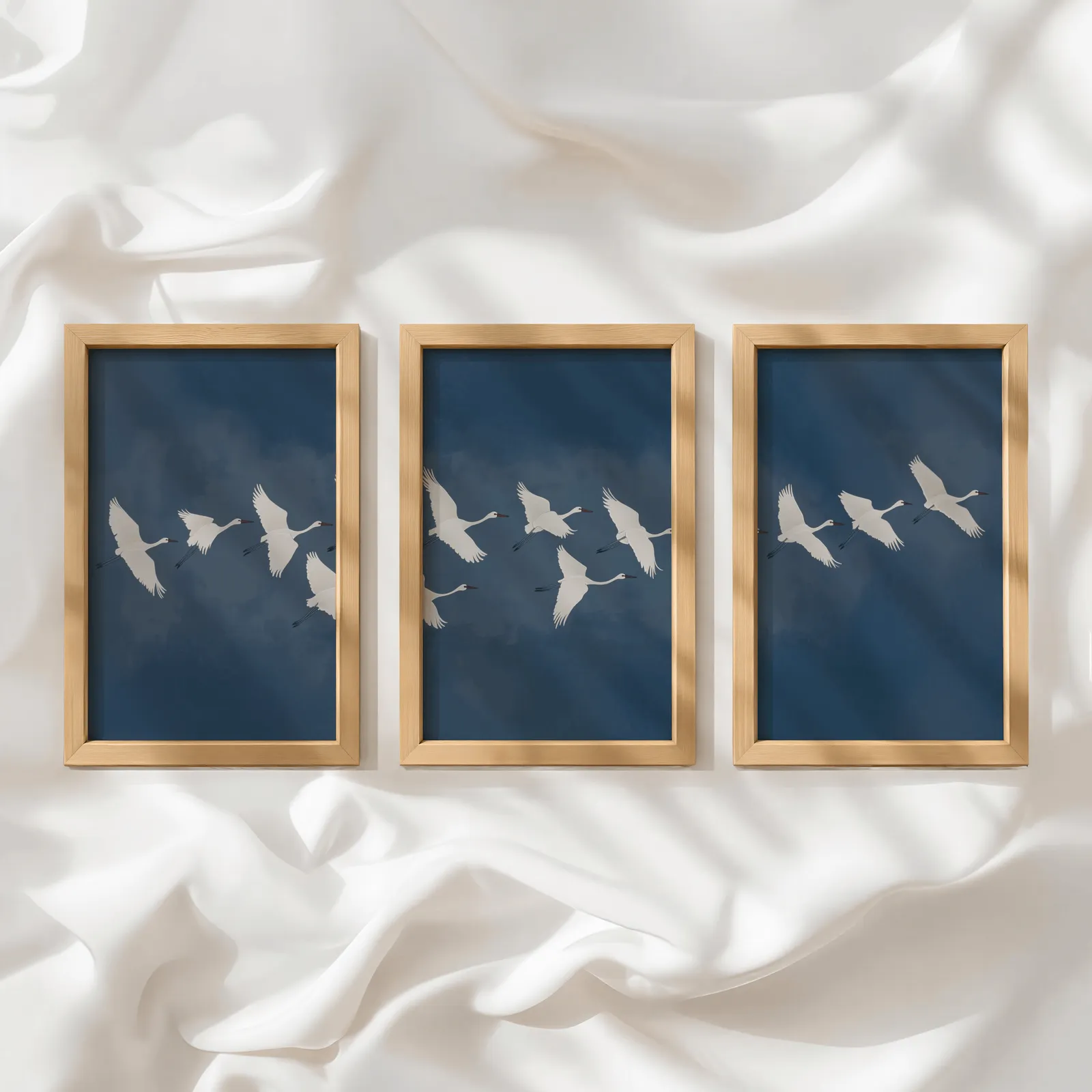 blue crane triptych wall art set, in a row atop rumpled white silky fabric