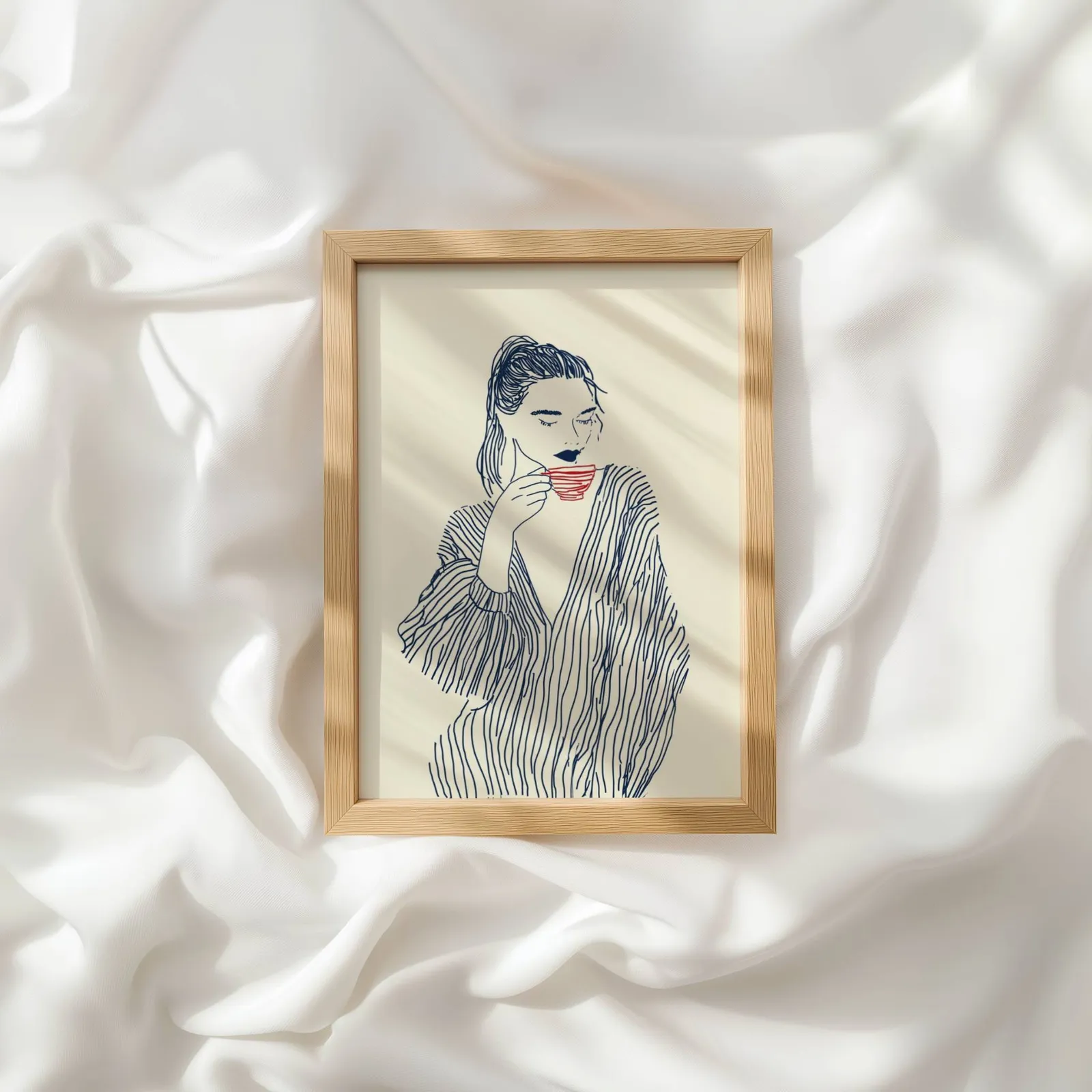 minimalist line art woman drinking coffee wall art, resting atop rumpled white silky fabric