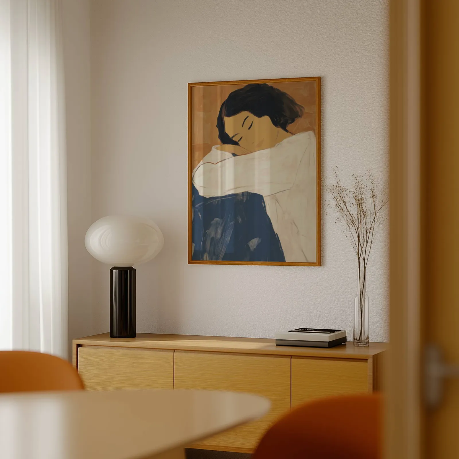 abstract woman wall art in blue and terracotta, above a light wood sideboard beside a bulbous black lamp