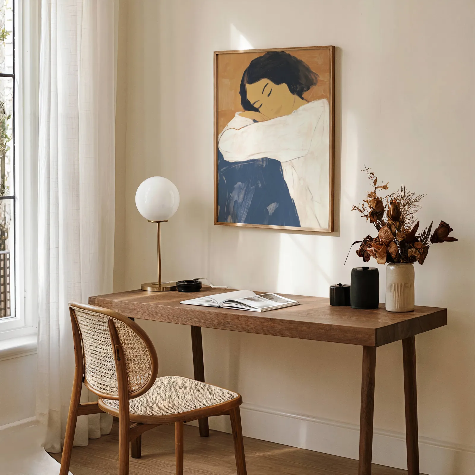 abstract woman wall art in blue and terracotta, above a wooden desk with a globe lamp and dried flowers
