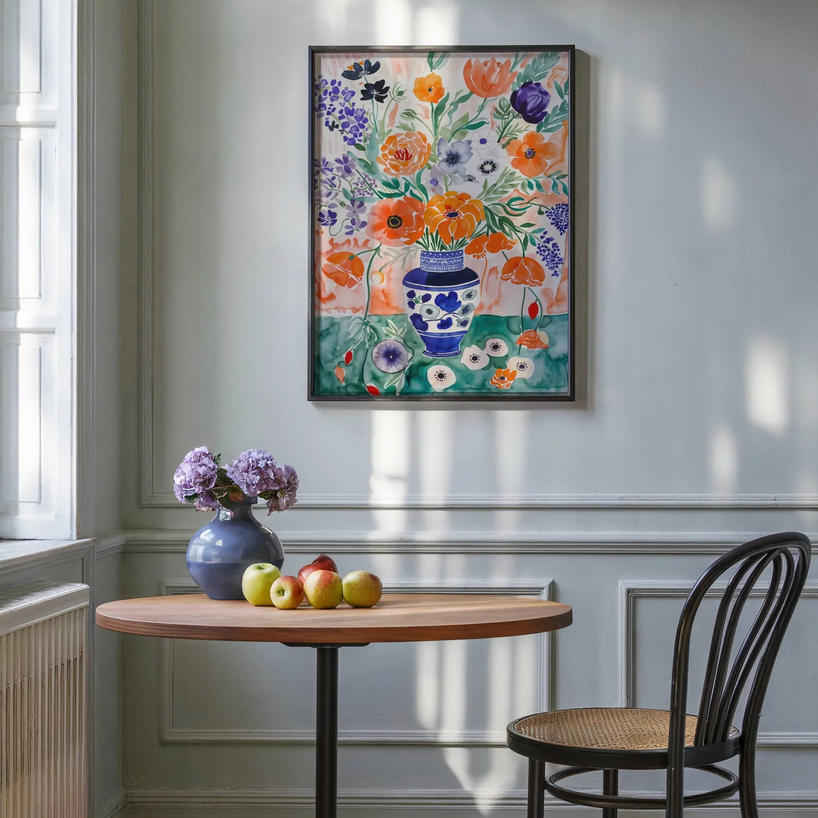 colorful floral wall art with blue vase, above a round wooden table with apples and a blue vase