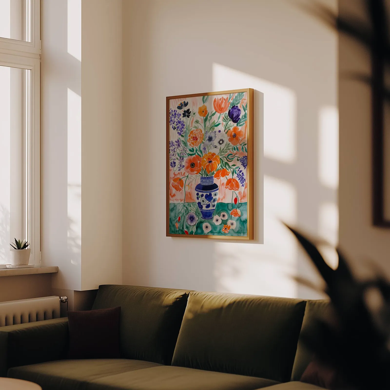 colorful floral wall art with blue vase, above an olive velvet sofa in raking afternoon light