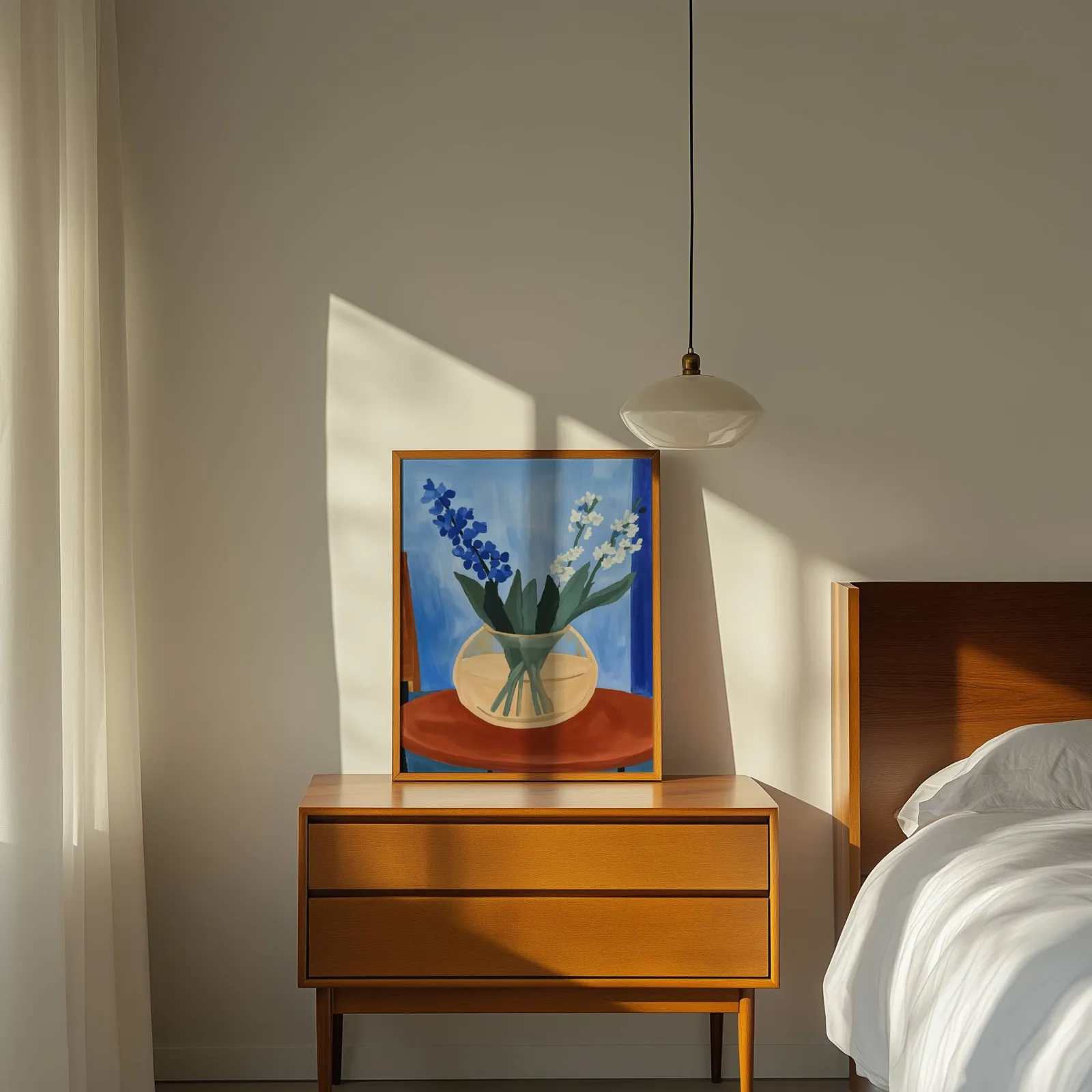 blue floral still life wall art in vase on terracotta table, propped on a wooden dresser beside a pendant lamp