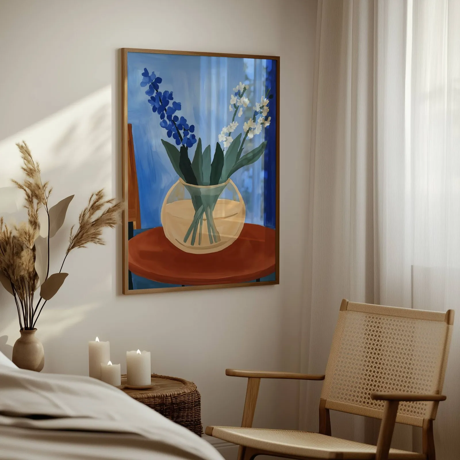 blue floral still life wall art in vase on terracotta table, above a woven side table with lit candles and pampas grass