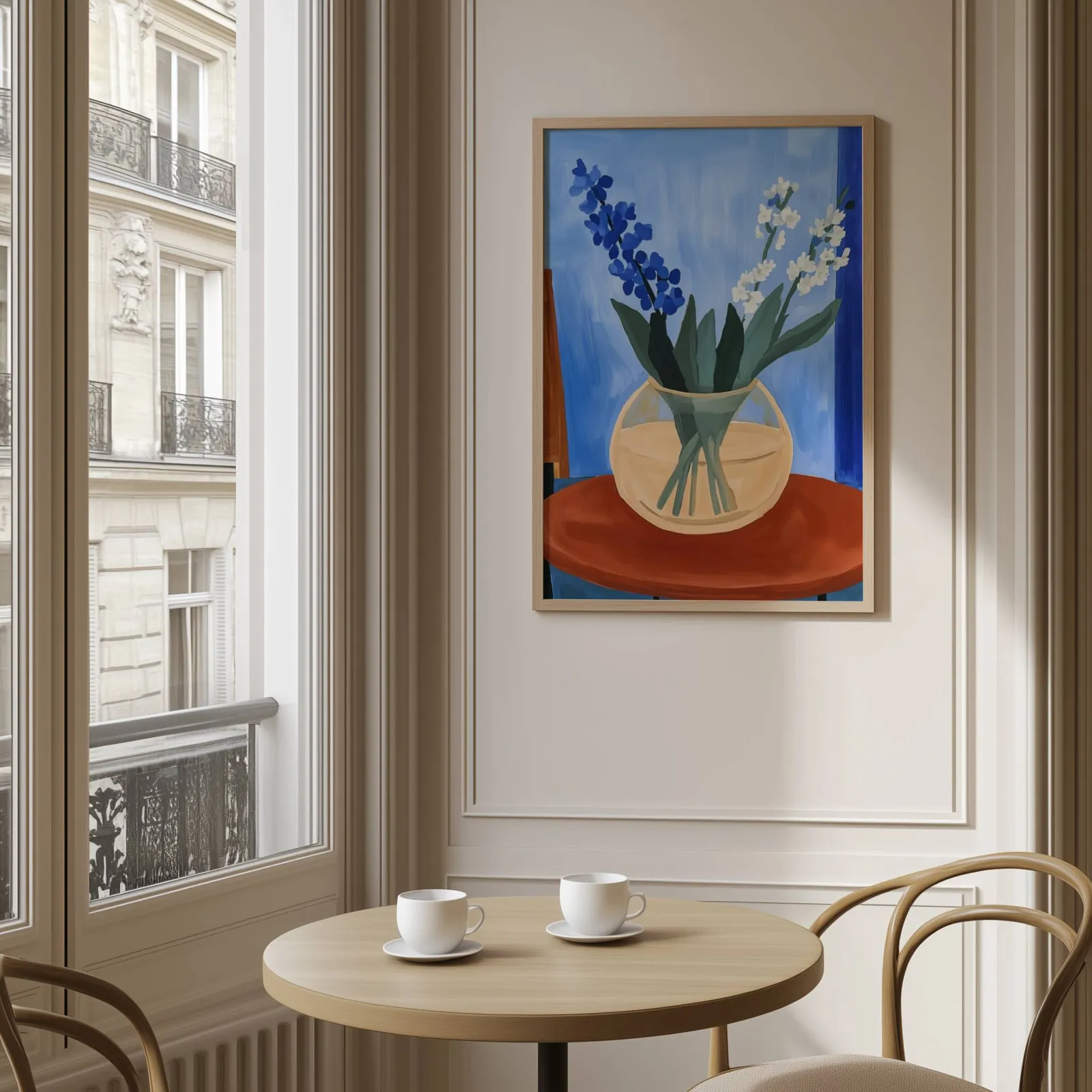 blue floral still life wall art in vase on terracotta table, above a round café table set with two coffee cups