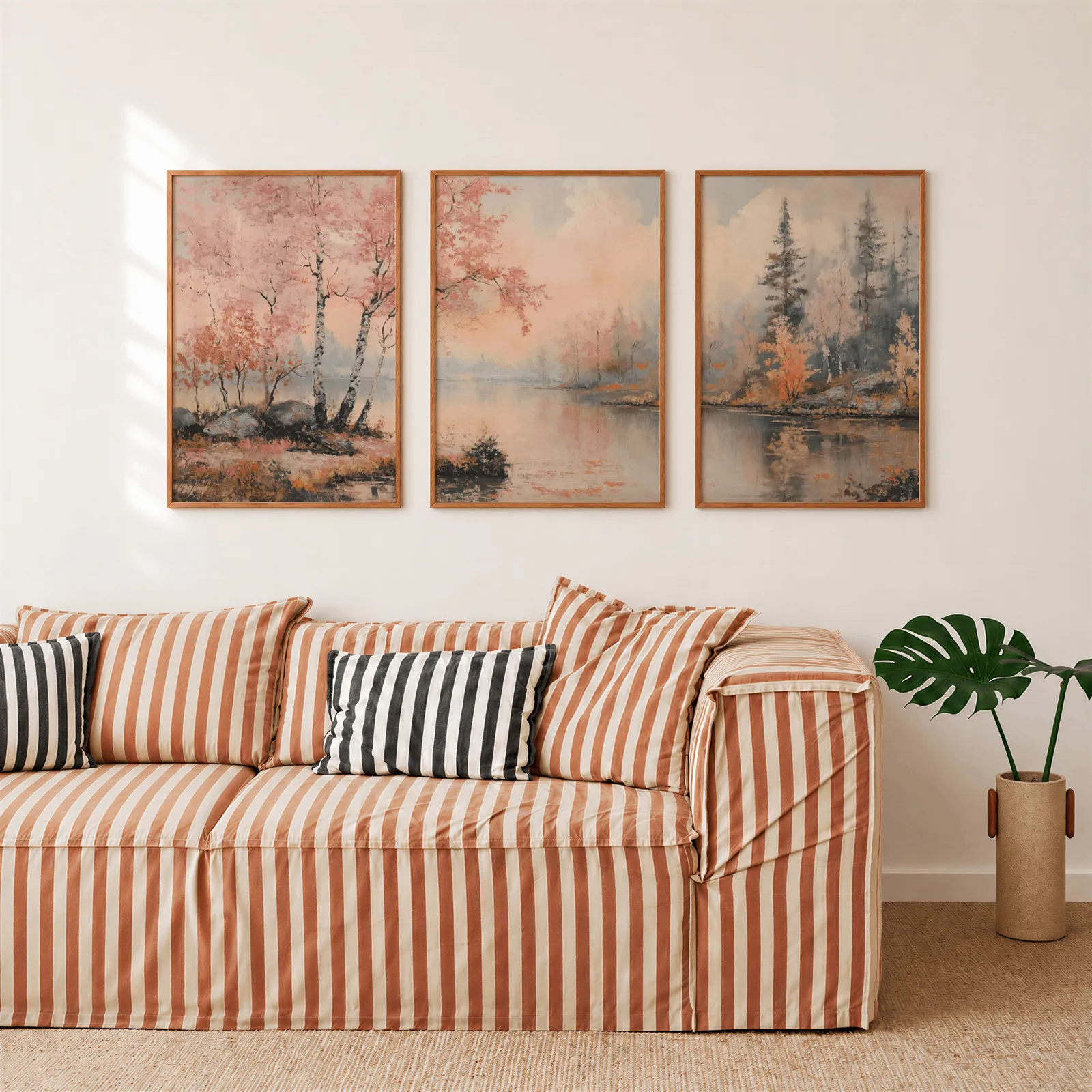 pink misty forest lakeside triptych wall art, above a rust-striped sofa beside a potted monstera