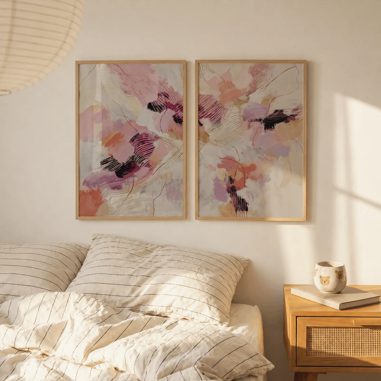 pink and orange abstract wall art set, above a striped linen bed beside a paper lantern shade
