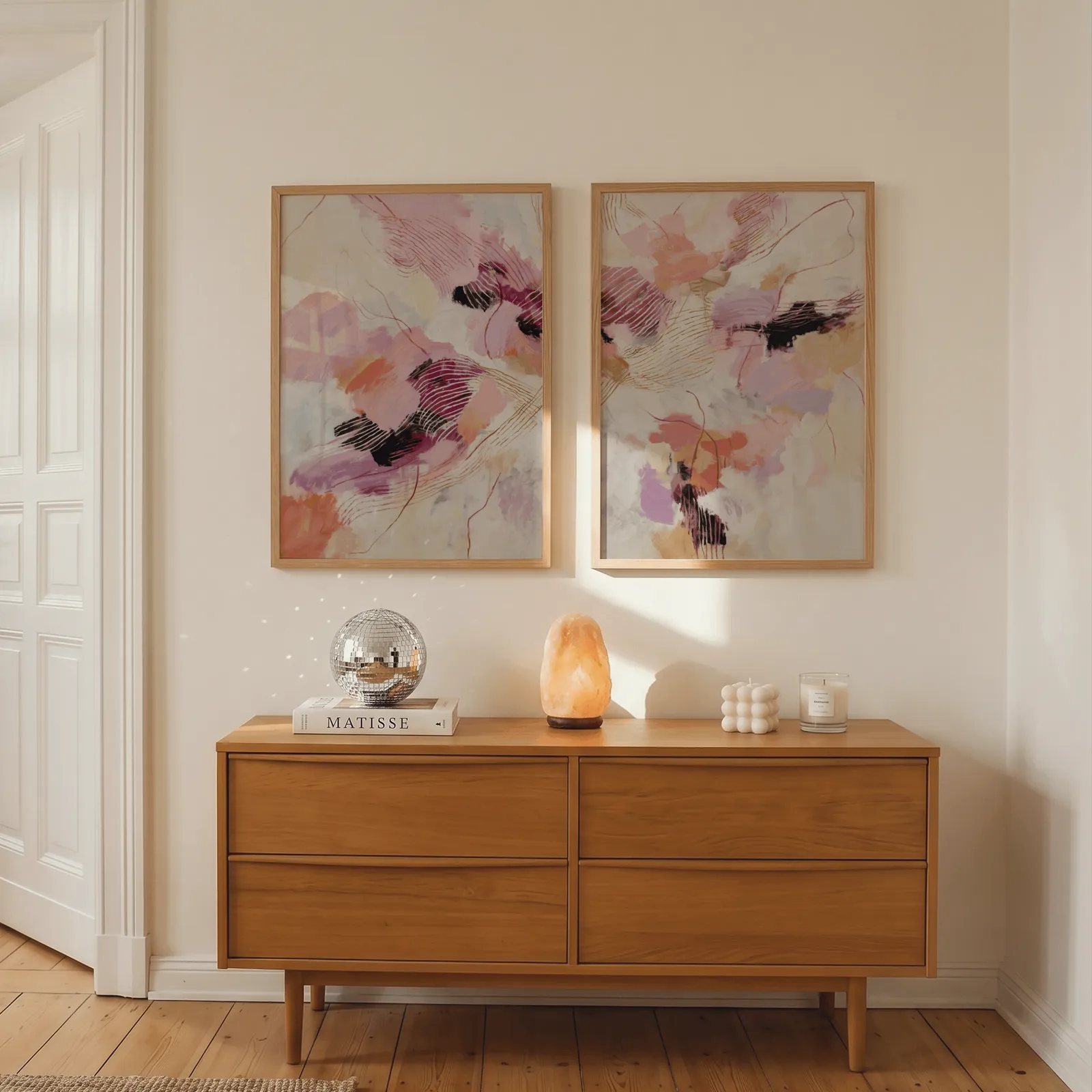 pink and orange abstract wall art set, above a wooden dresser with a salt lamp and disco ball