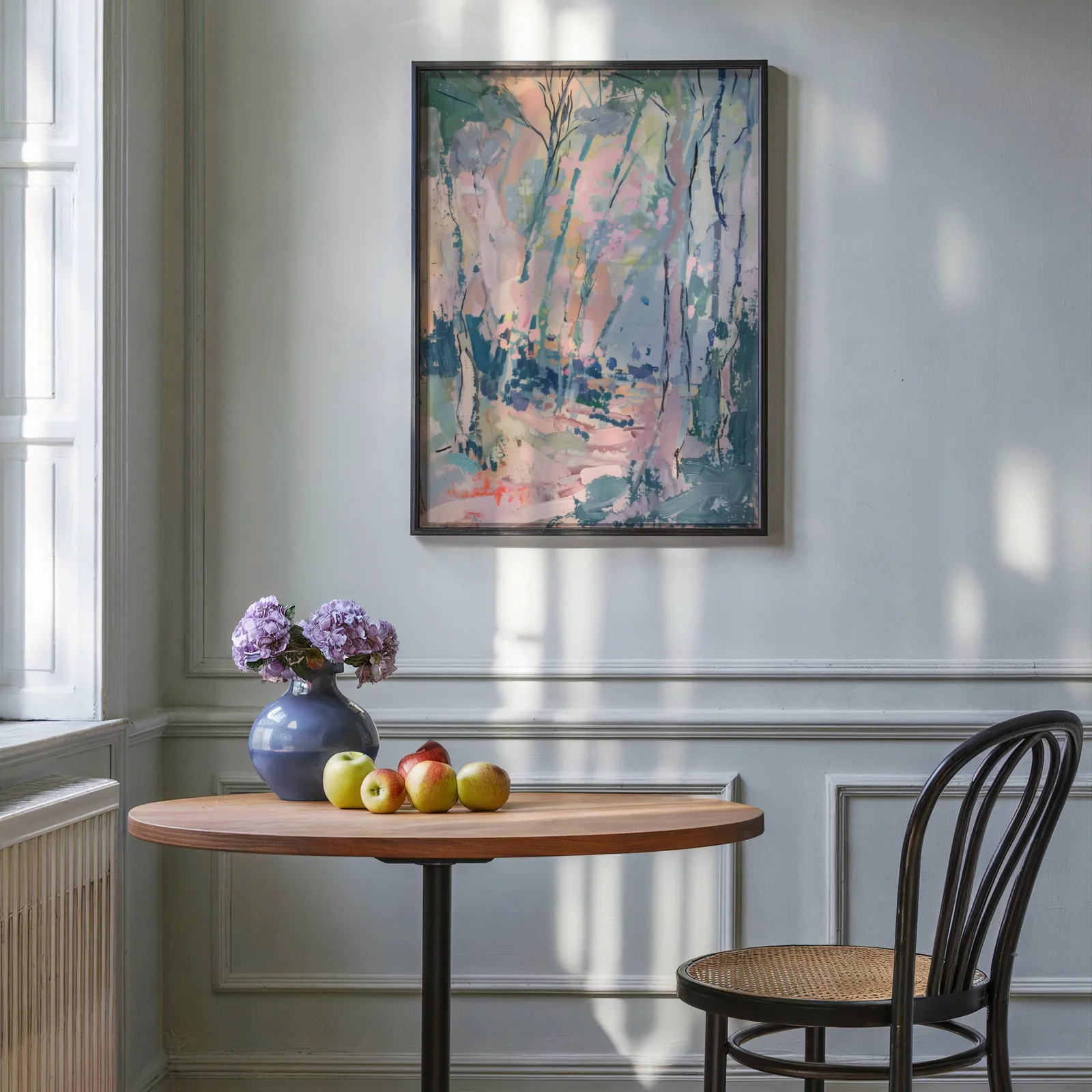 pink and green abstract forest wall art, above a round wooden table with apples and a blue vase