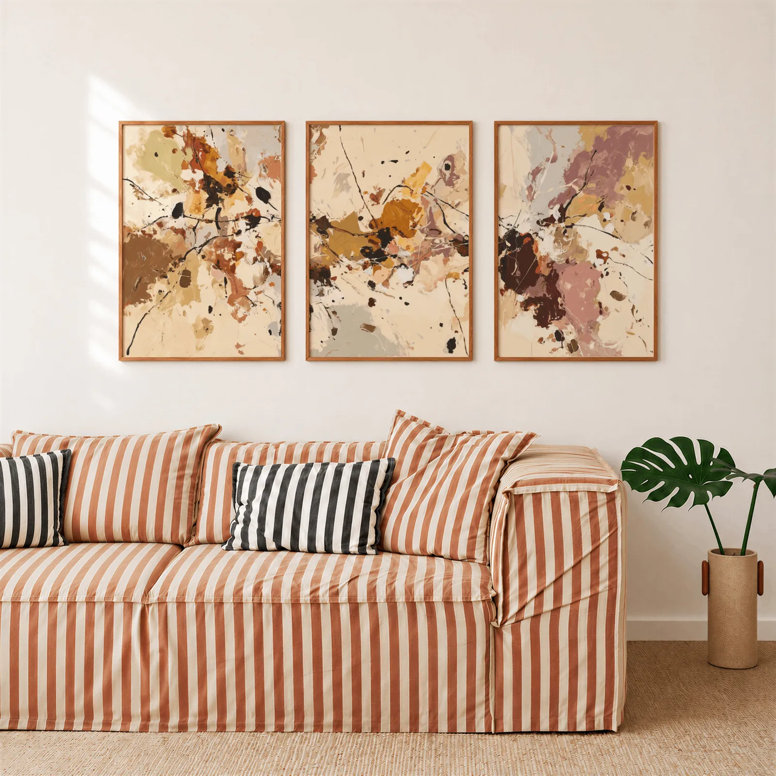 terracotta abstract three piece wall art set, above a rust-striped sofa beside a potted monstera