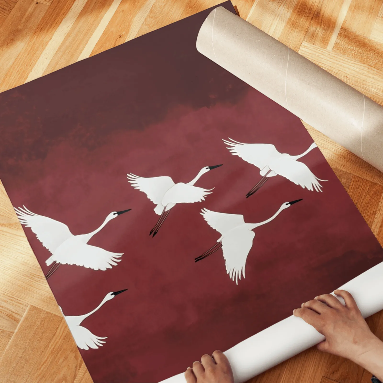 burgundy crane flight triptych wall art, unrolled across a herringbone wood floor by hand