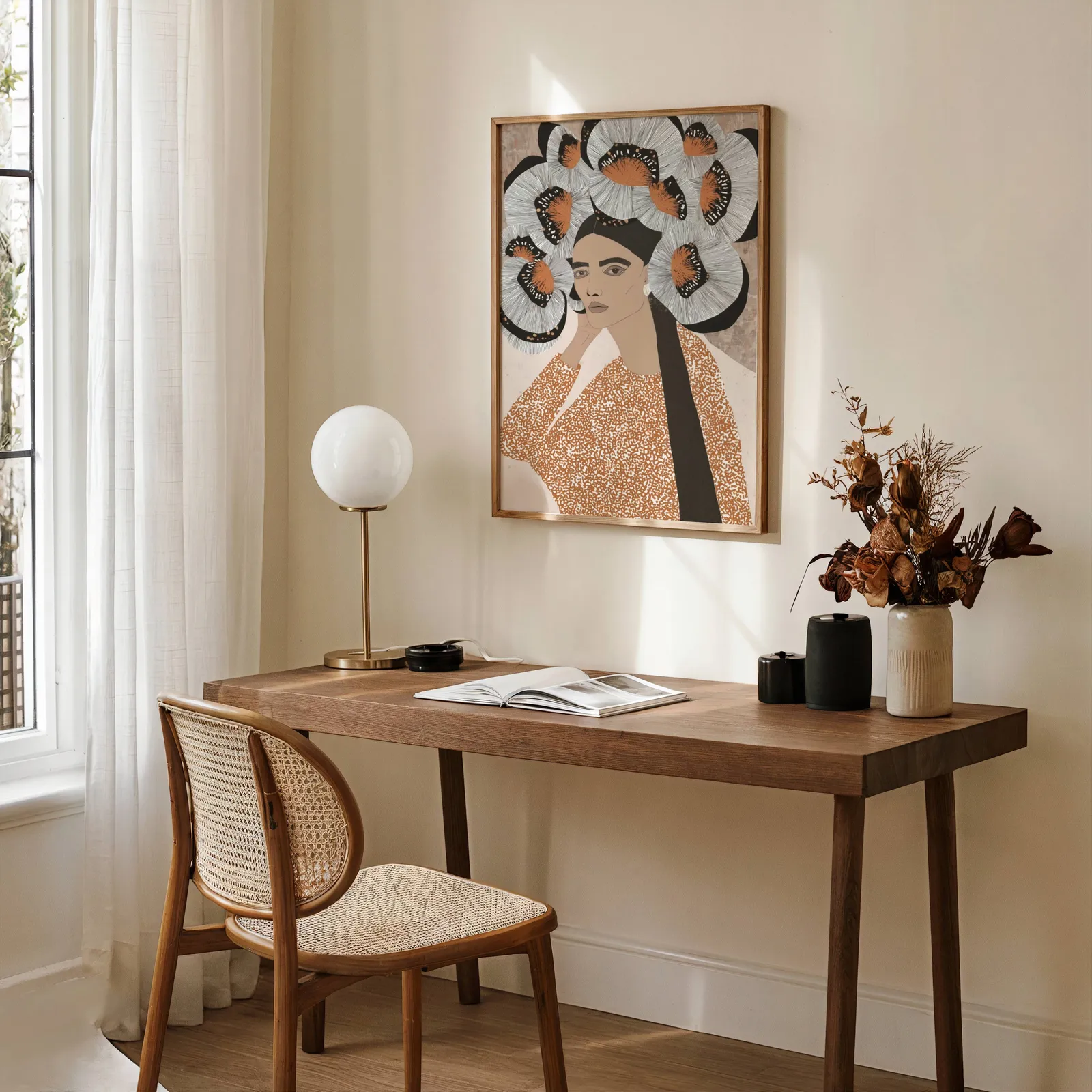 terracotta portrait wall art with butterfly crown, above a wooden desk with a globe lamp and dried flowers