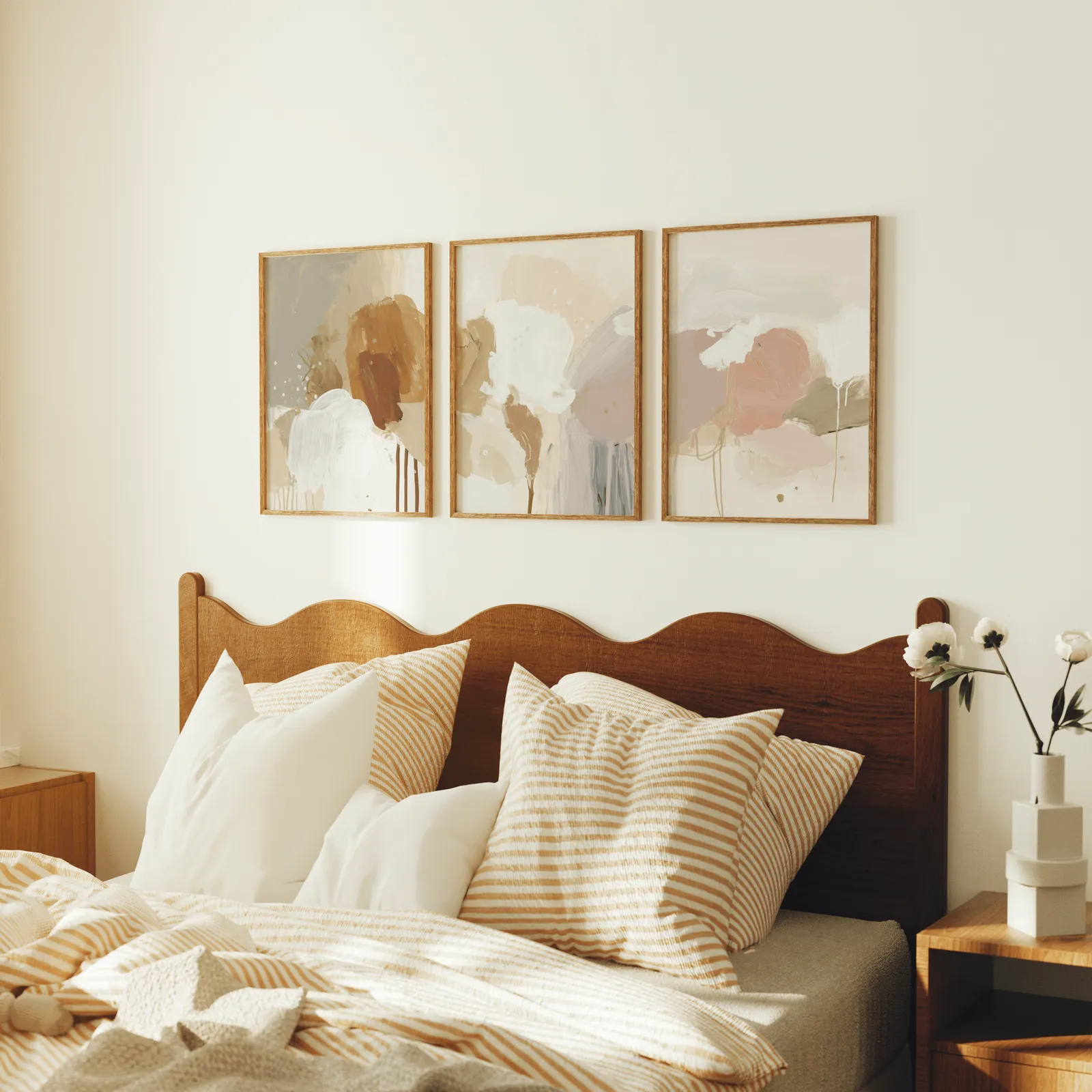 terracotta abstract wall art set of 3, above a scalloped wooden headboard with striped pillows