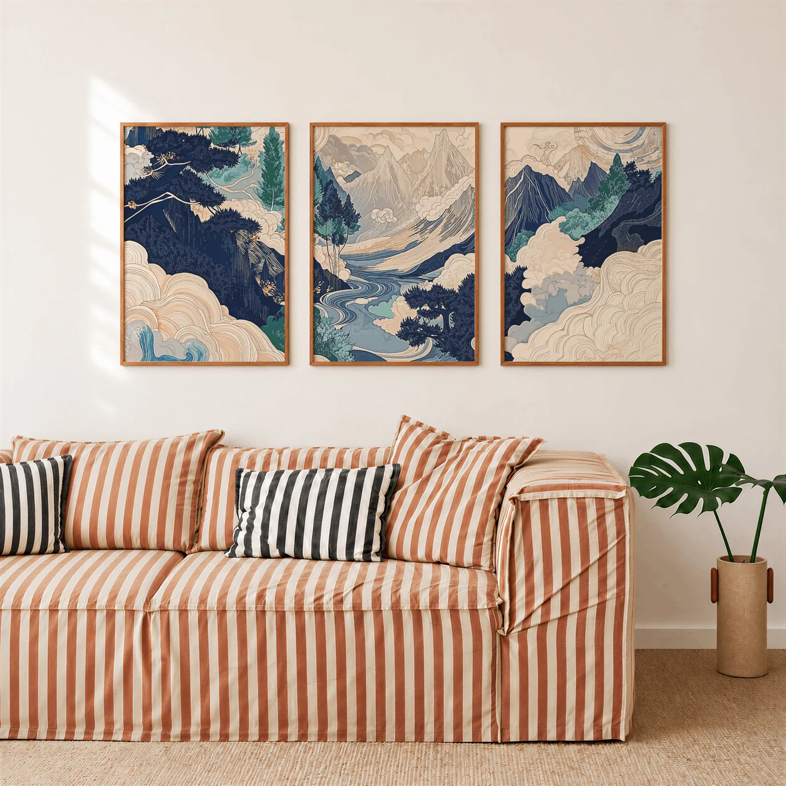 blue japandi mountain landscape triptych wall art, above a rust-striped sofa beside a potted monstera