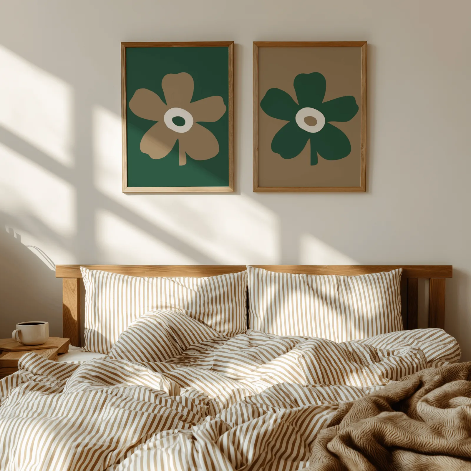green and brown botanical flower wall art set of two, above a wooden headboard with striped bedding and raking sunlight