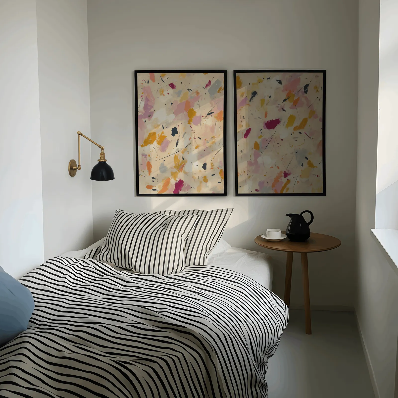 colorful abstract confetti wall art set of two, above a striped bed beside a brass swing-arm lamp